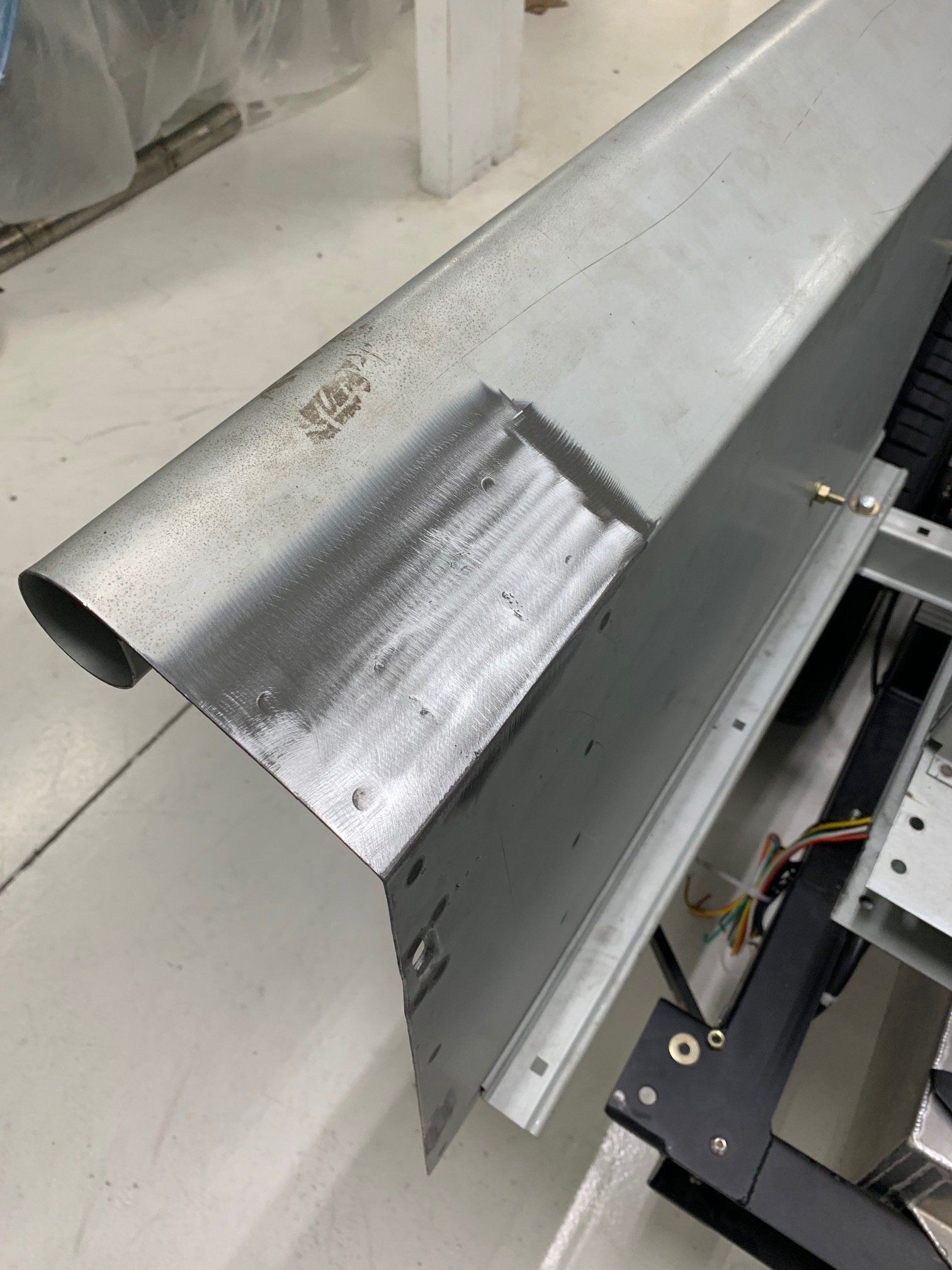 Damaged gray metal sheet with a bent, scratched section on a workbench