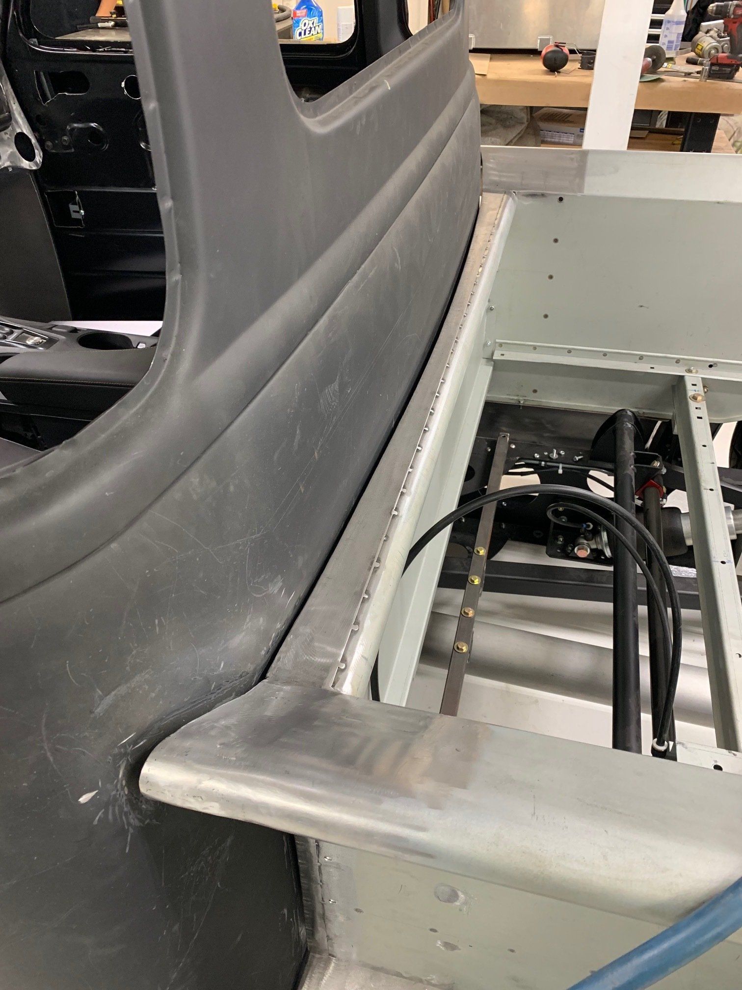 Gray upholstered chair beside a metal workstation with exposed cables and machinery.