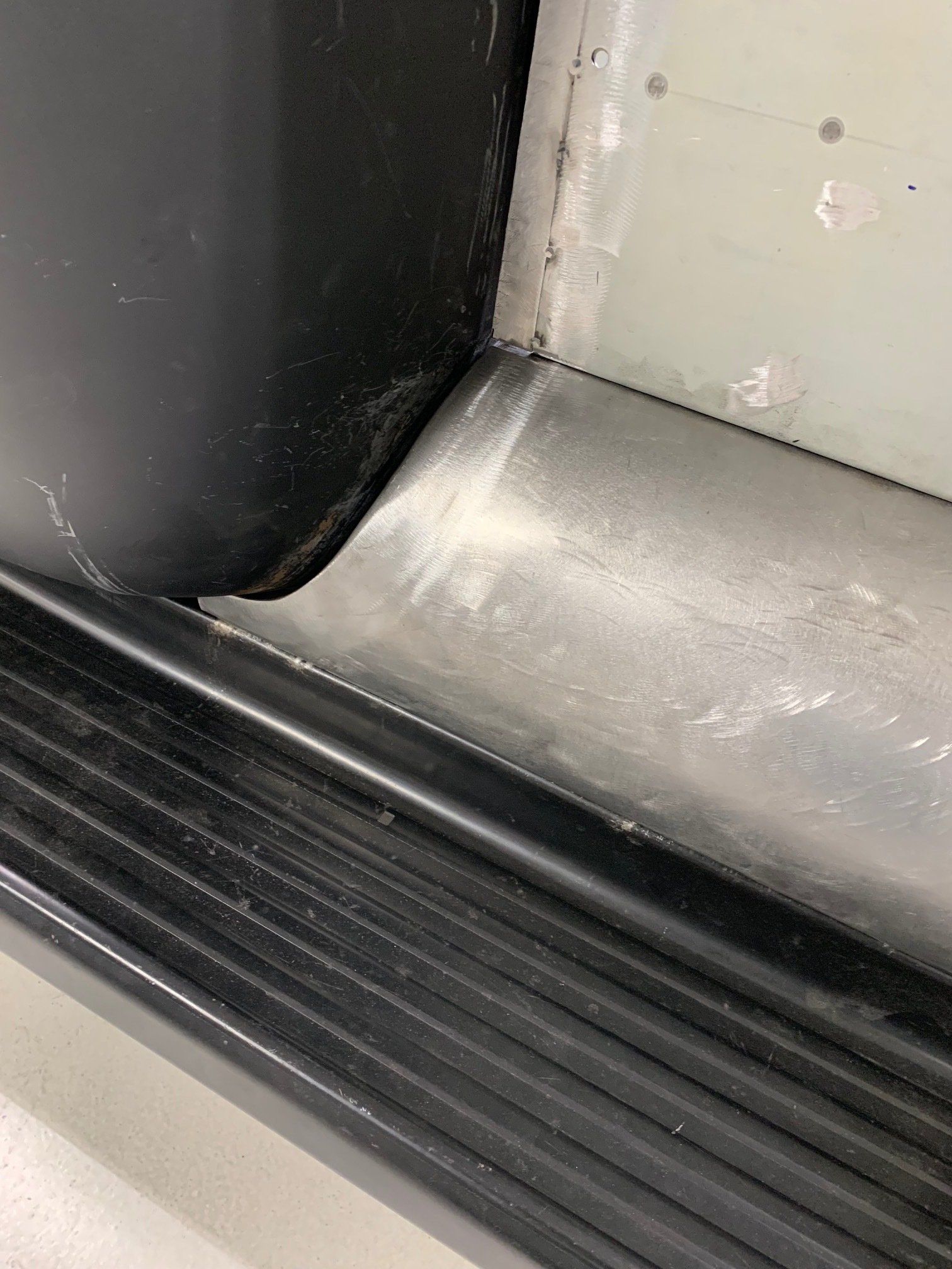 Close-up of a black rubber door seal and light gray metal threshold with minor scuffs.