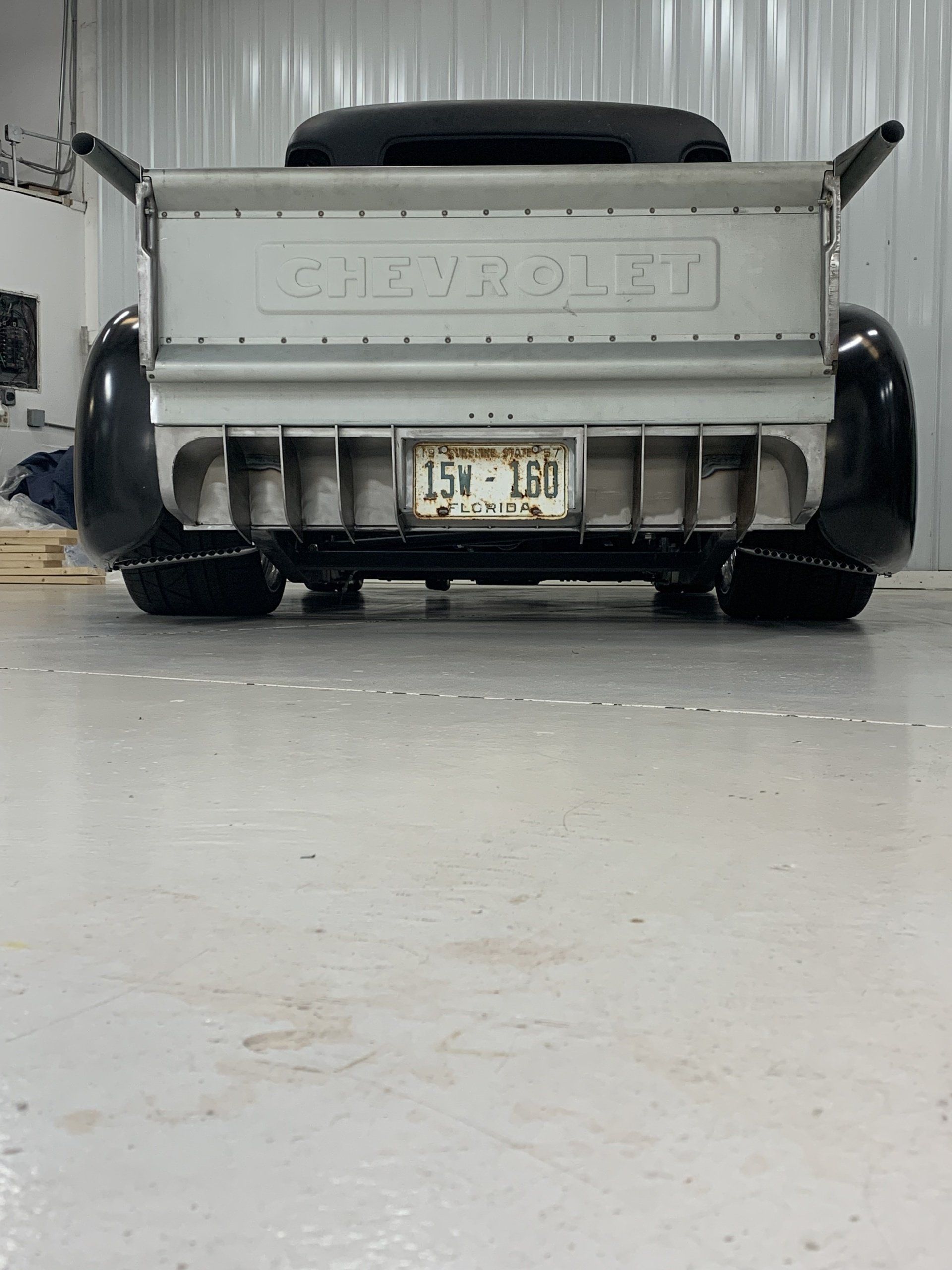 Rear view of a gray GMC truck parked indoors, with a Michigan license plate and large black tires.