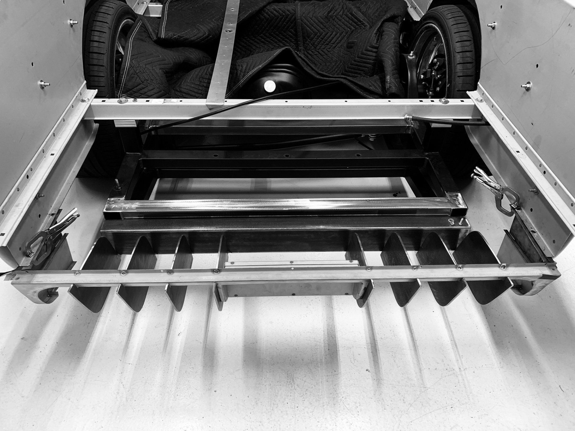Open truck bed with a metal tailgate ramp and four off-road tires visible inside