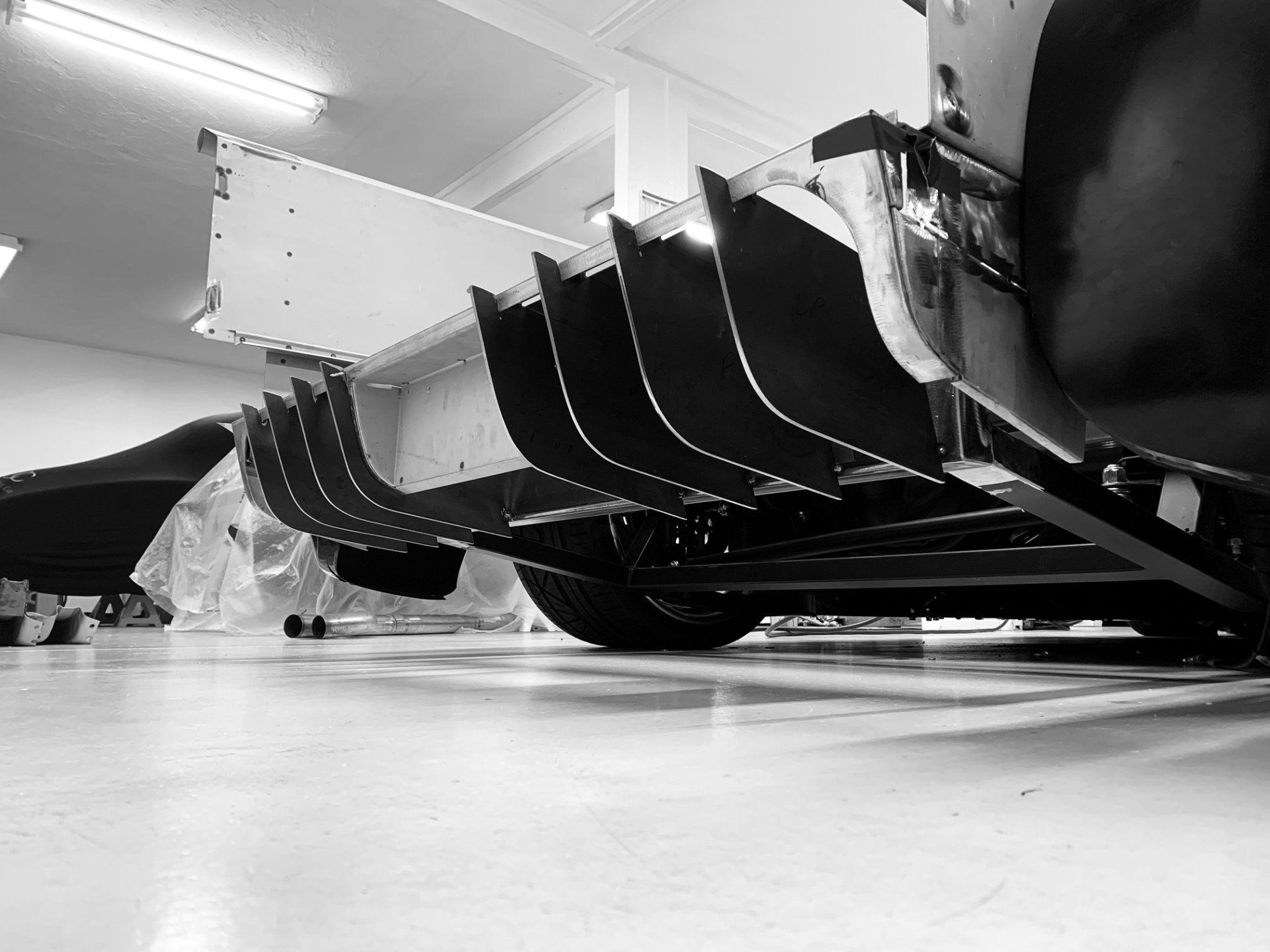 Black-and-white low-angle view of a car’s undercarriage in a workshop or garage