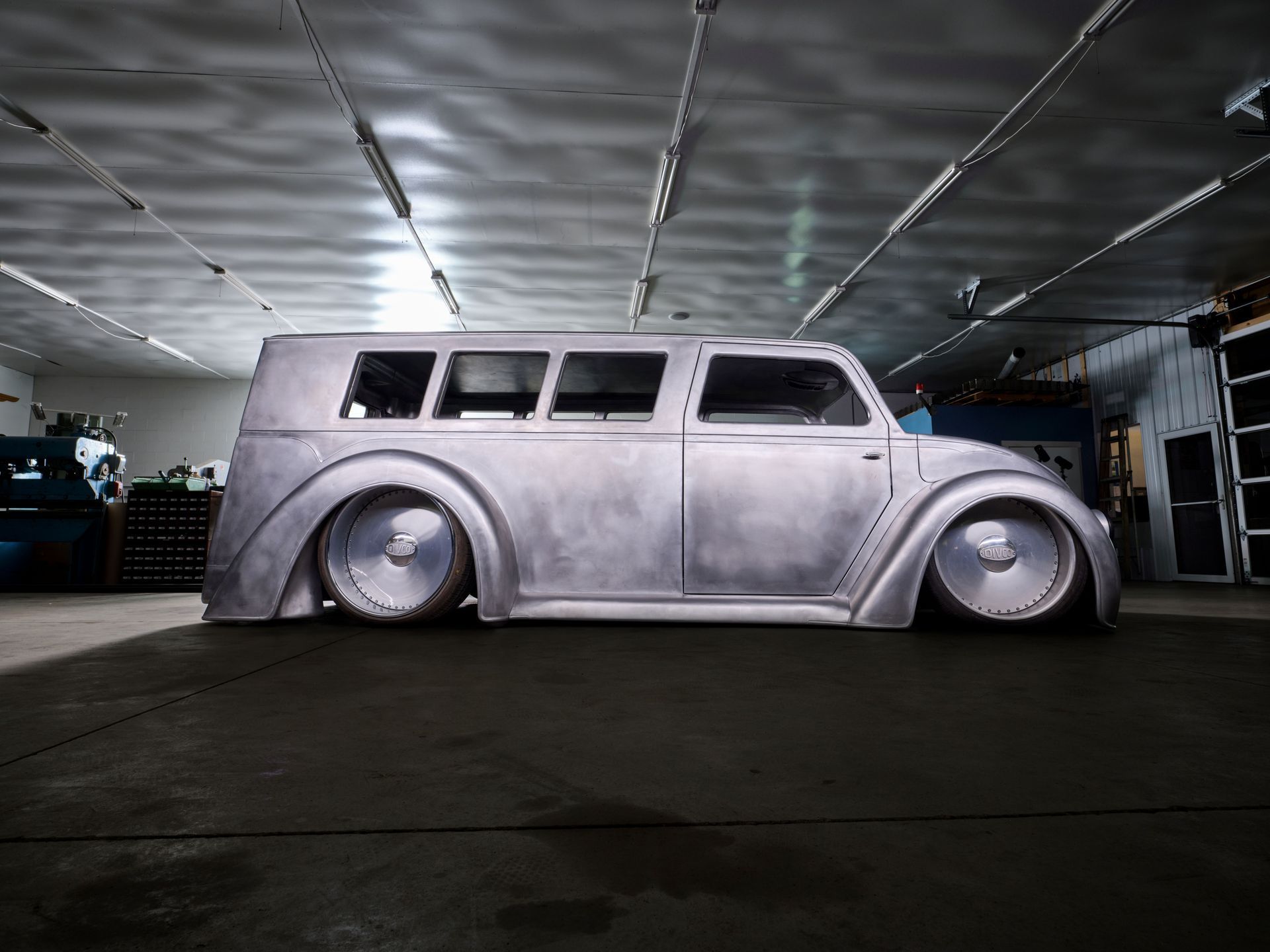Lowrider-style white van with extreme suspension, parked in a dim garage