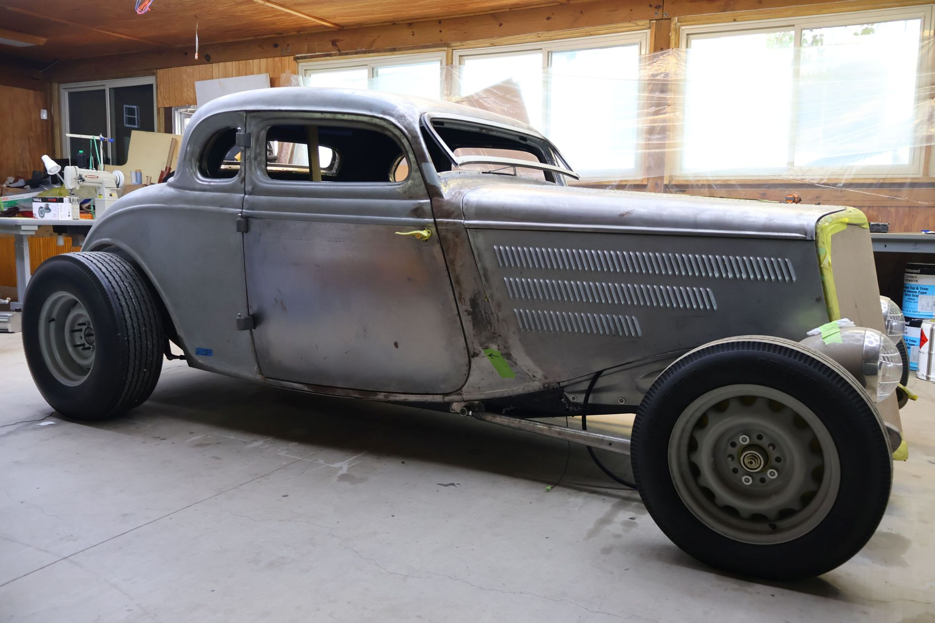 Custom gray vintage hot rod in a garage, with exposed front engine and large rear tires