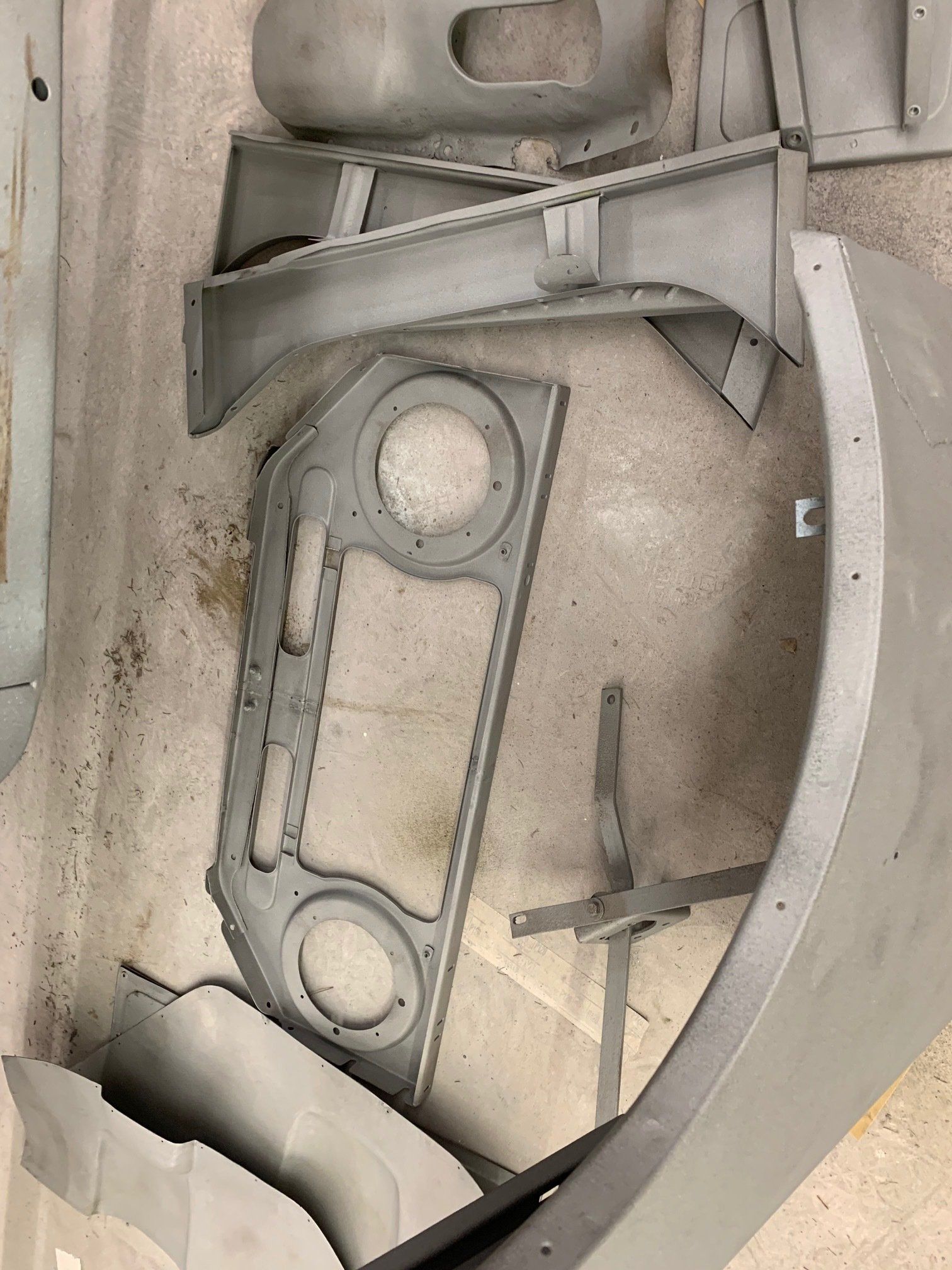 Assorted gray metal parts and plates stacked in a container or bin.