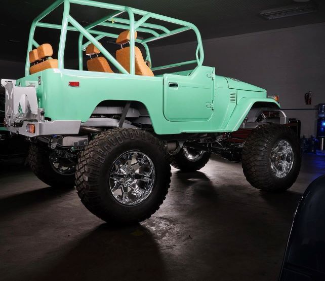 Mint green lifted off-road truck with orange seats in a dark garage