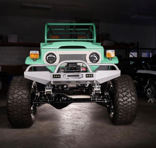 Front view of a mint-green off-road truck with oversized tires in a dark garage.