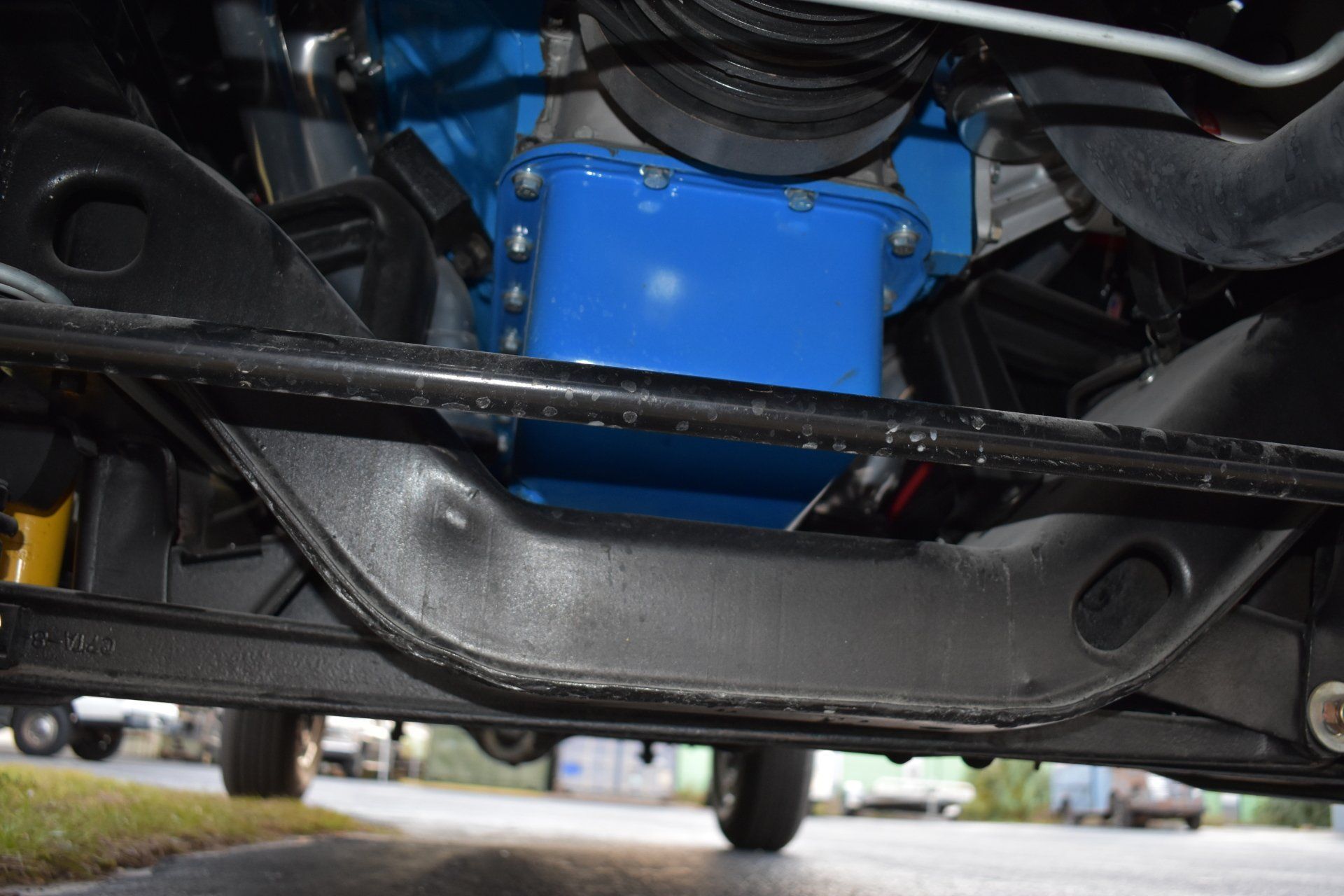 Undercarriage of a vehicle with a blue engine component and black suspension parts
