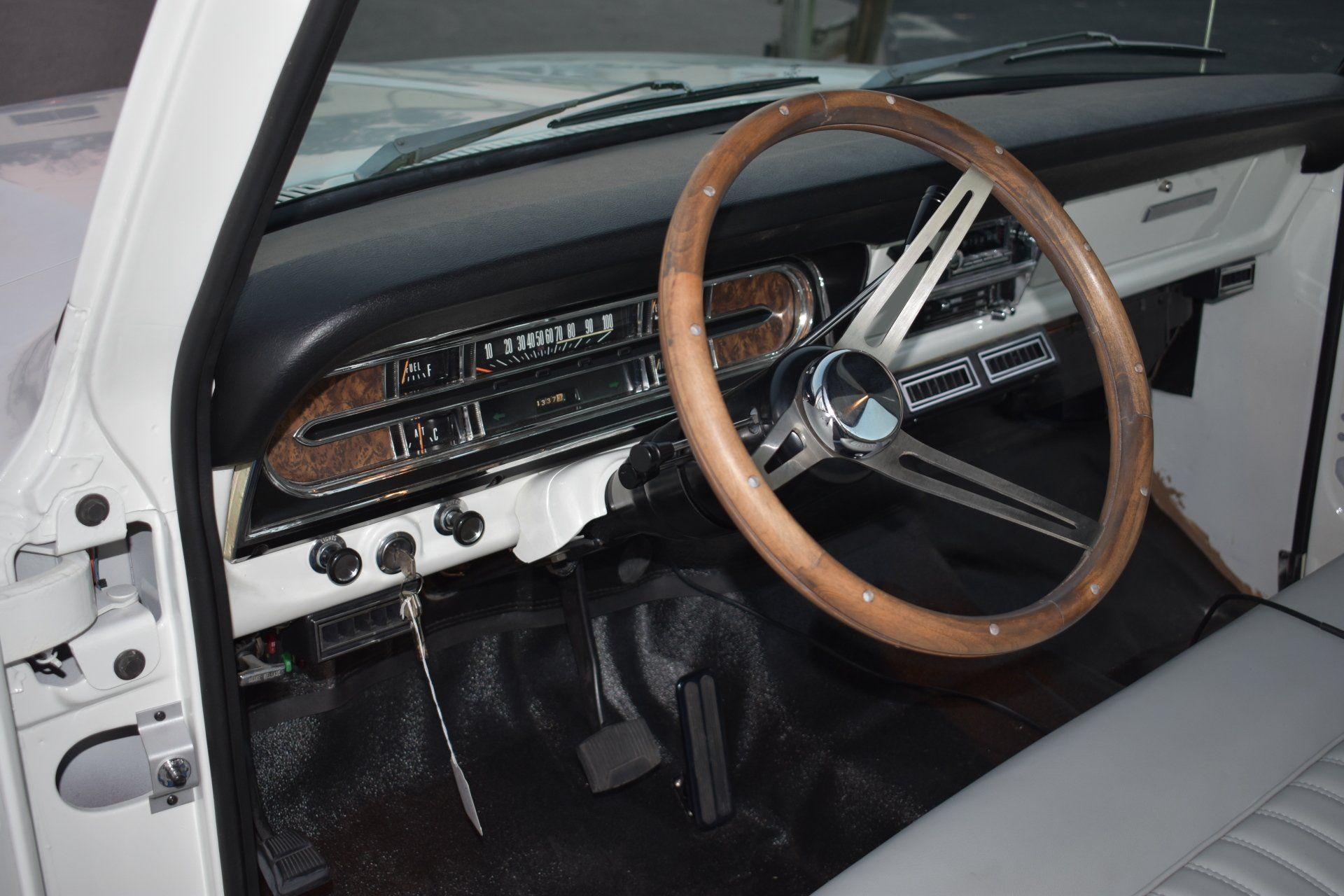 Classic car interior with wood-rim steering wheel, black dash, and gray seats
