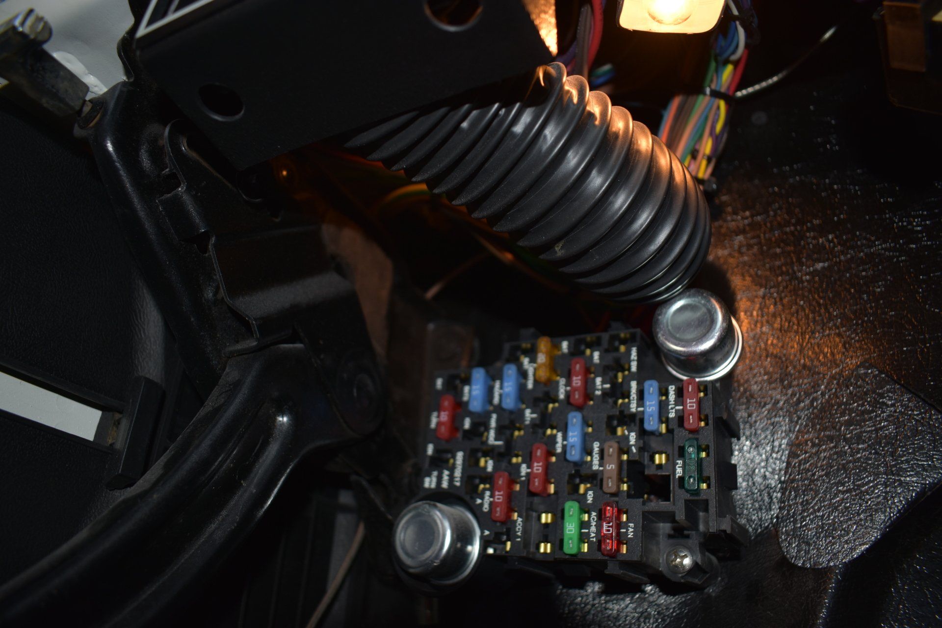 Car's interior fuse box with rows of colorful fuses beneath the dashboard.