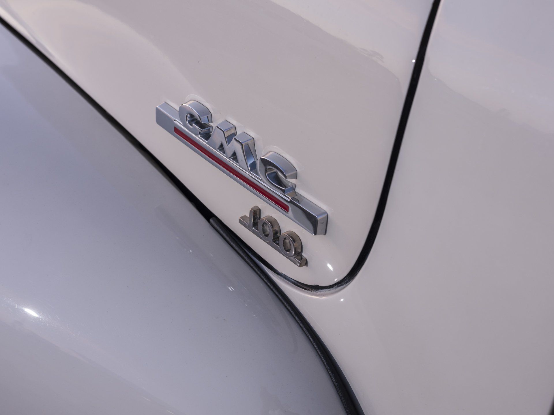 Close-up of a white GMC 4x4 truck badge on the rear tailgate.