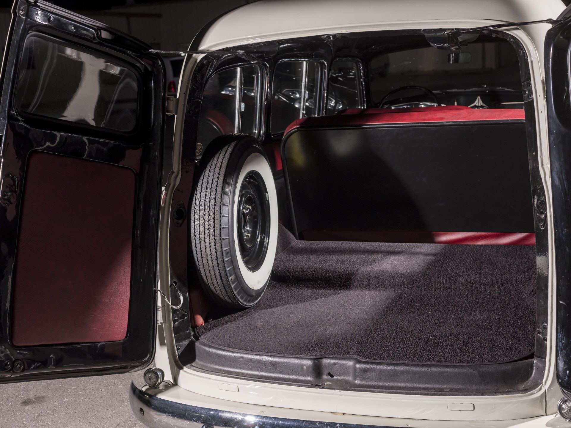 Open car trunk with a spare tire and black-and-red interior lining
