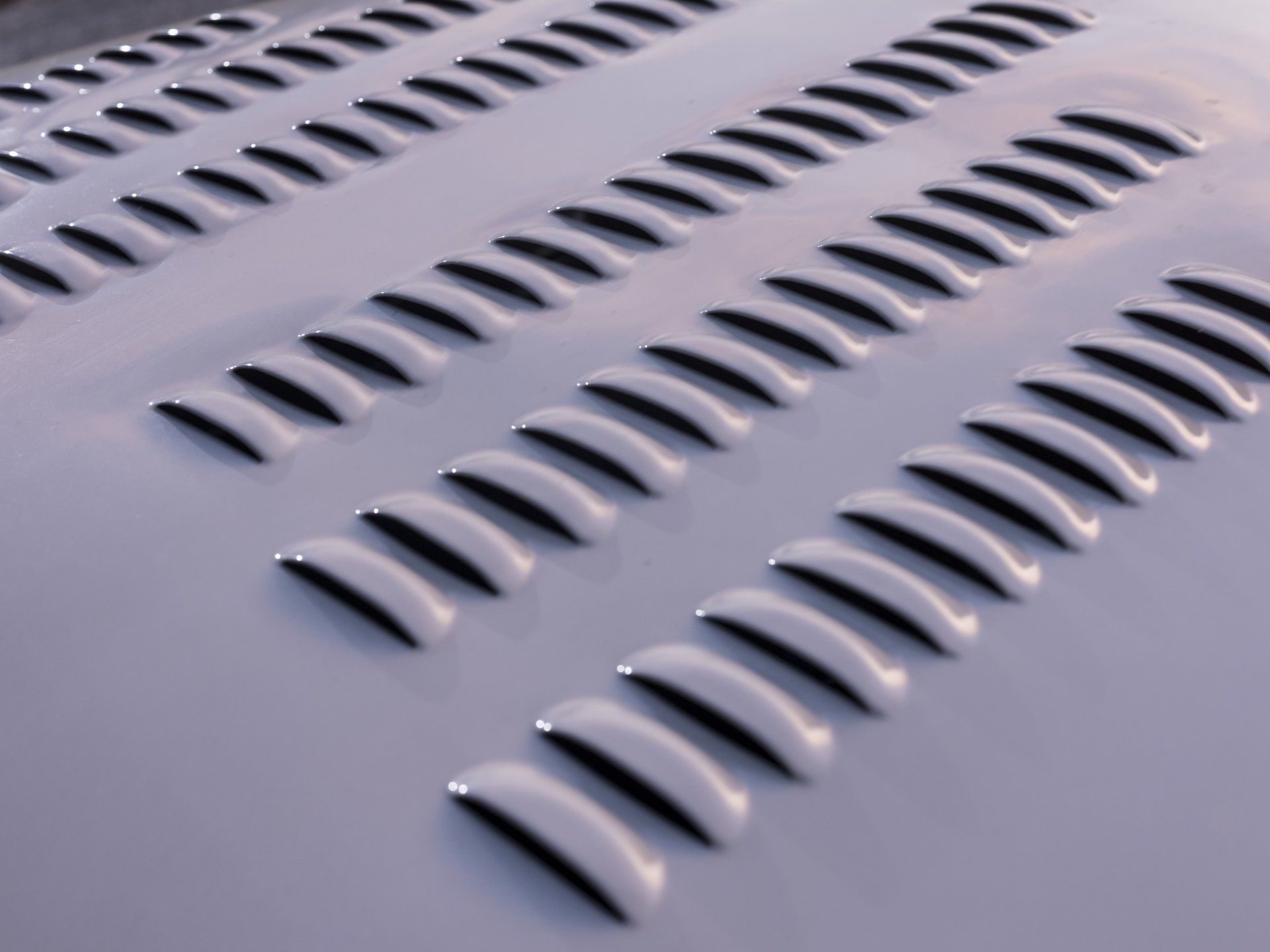 Rows of raised oval perforations on a light gray metal surface