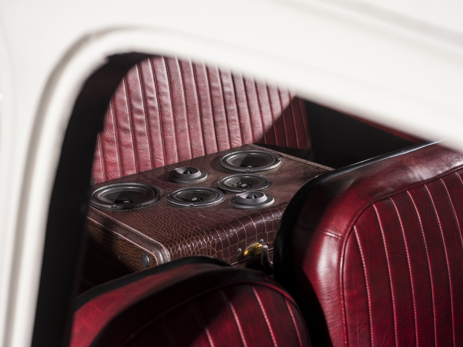 Vintage car interior with red striped seats and a built-in table holding cup holders