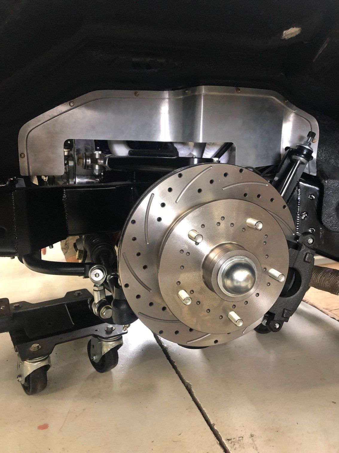 Close-up of a car’s exposed brake rotor and suspension assembly in a garage