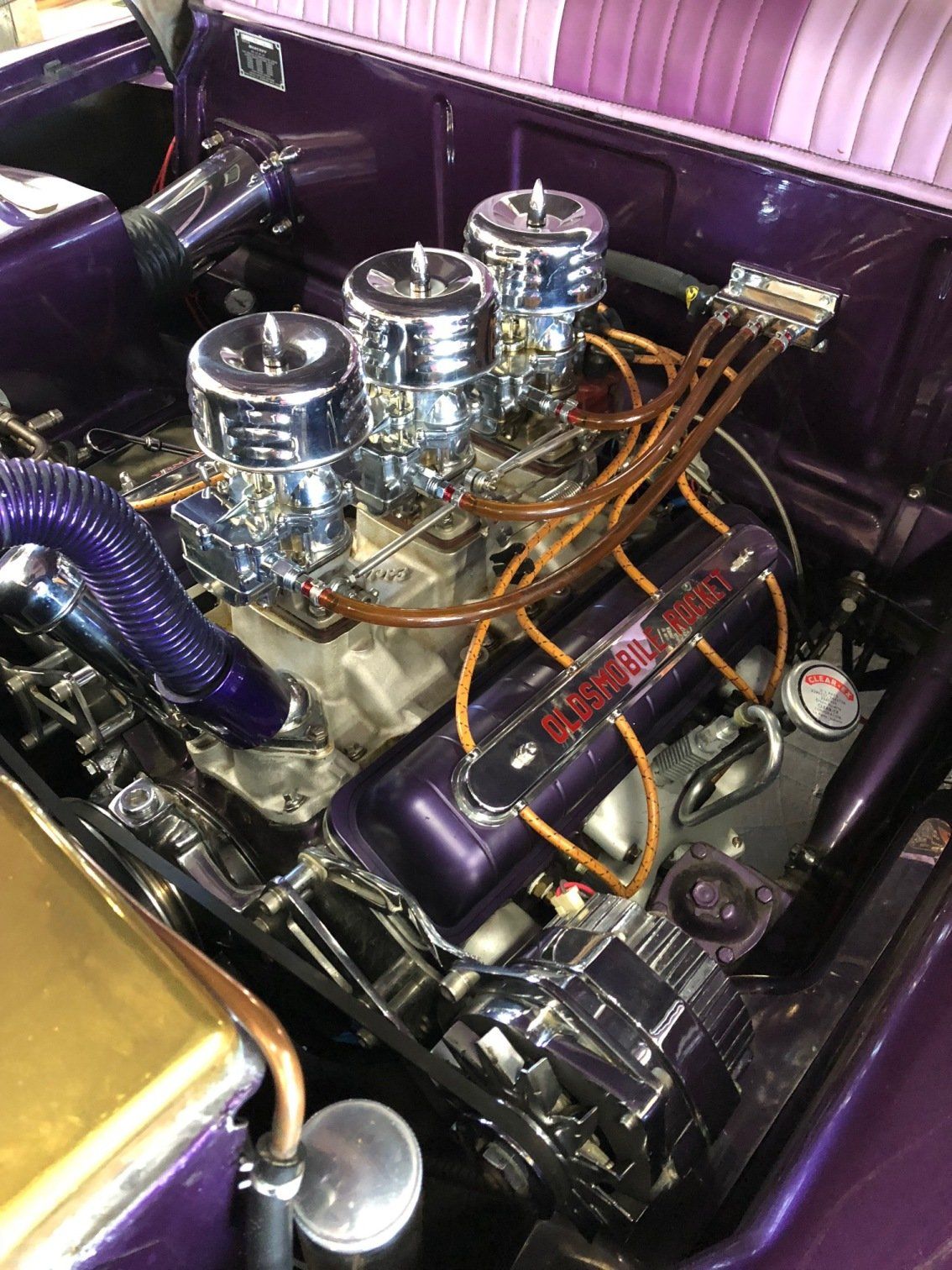 Custom purple car engine bay with polished chrome intake and orange wiring