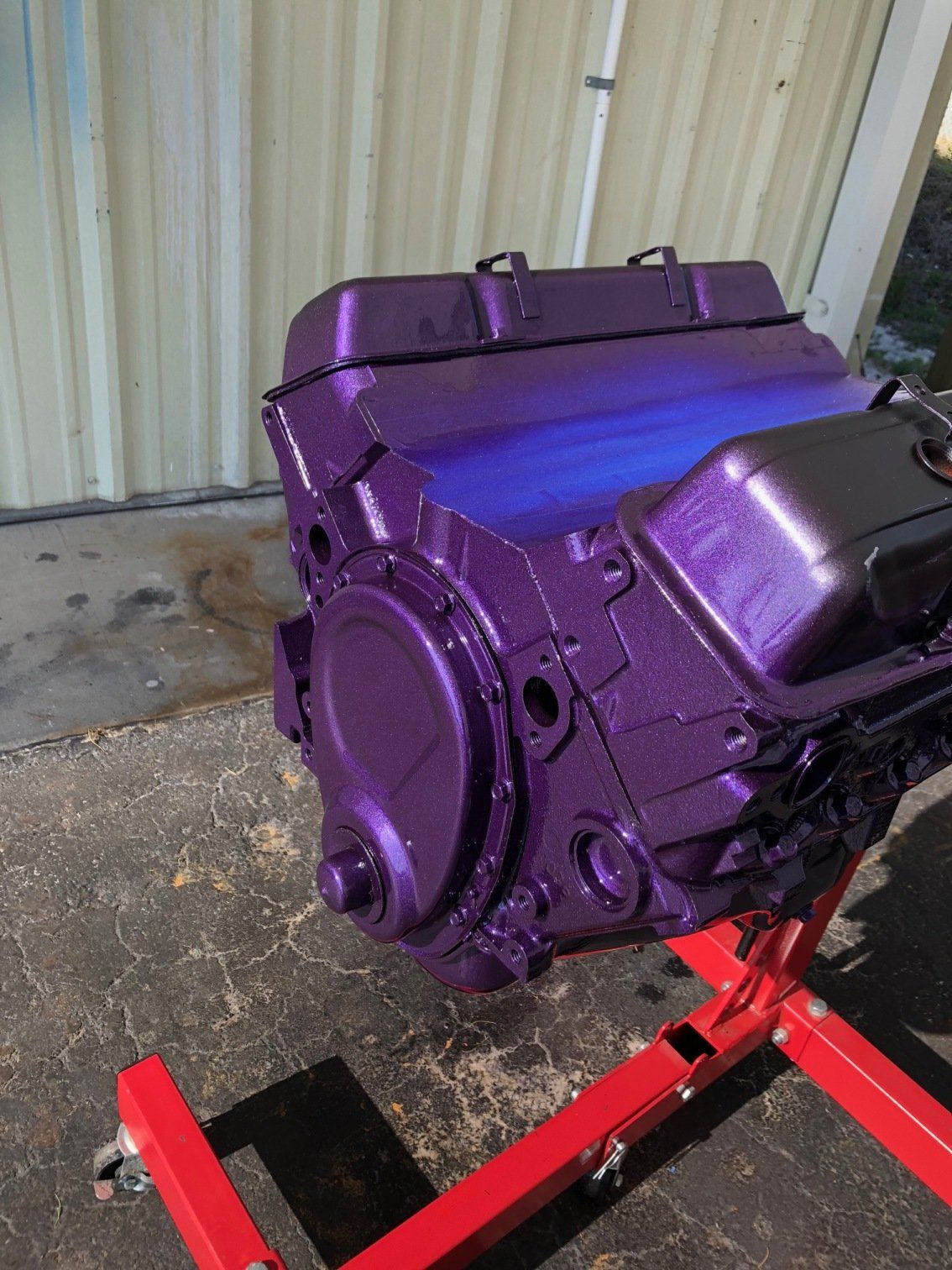 Purple-painted engine on a red stand in a workshop.