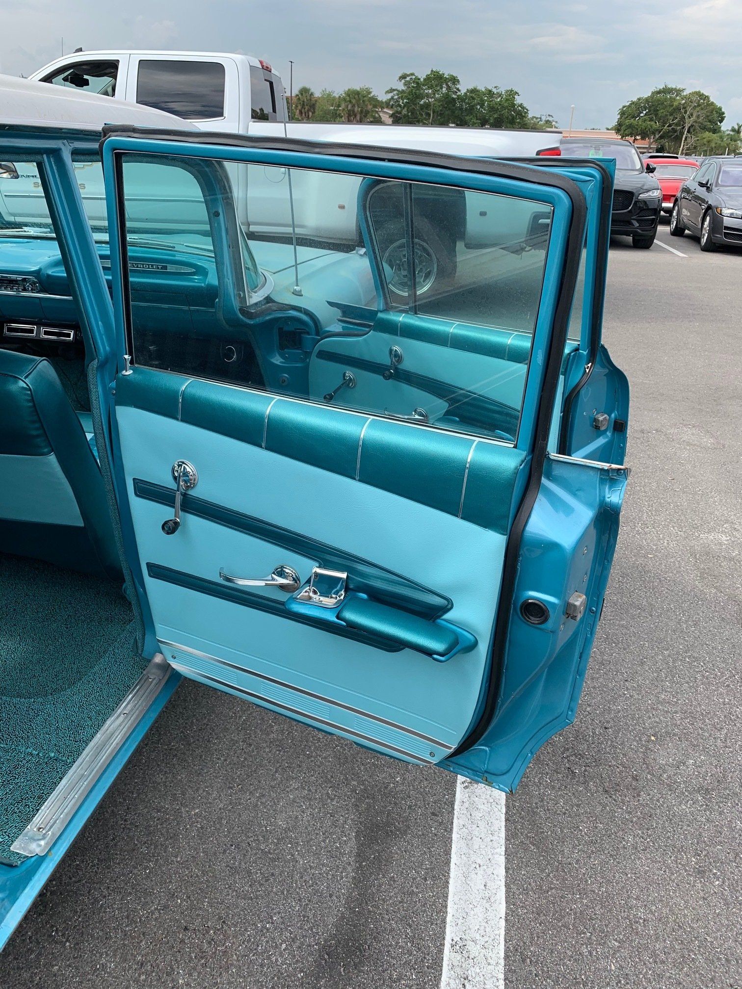 Turquoise car with its door open, showing the interior in a parking lot