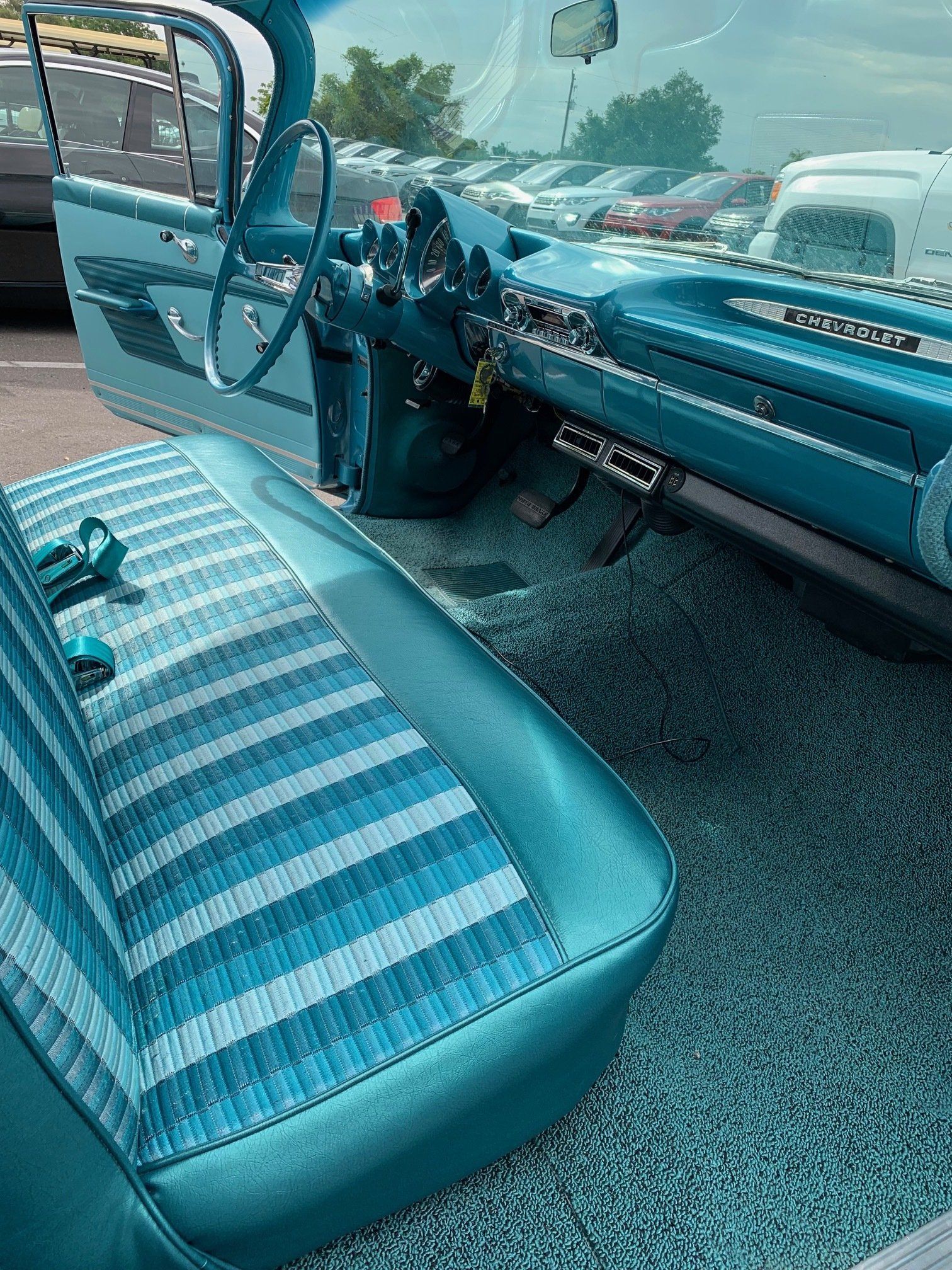 Vintage car interior with turquoise bench seat and dashboard, seen from the passenger side