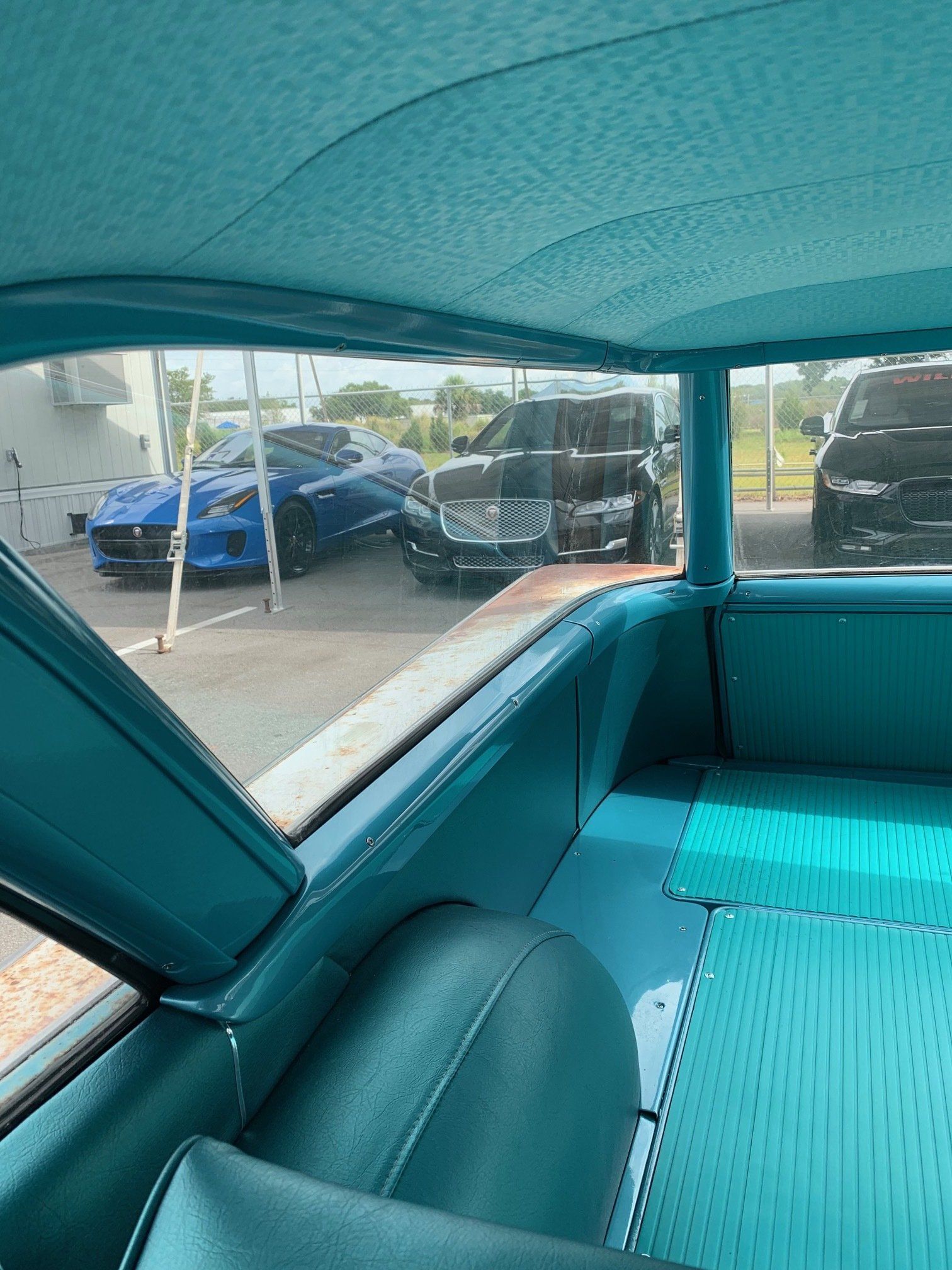 Teal car interior with rear window view of parked cars in a lot