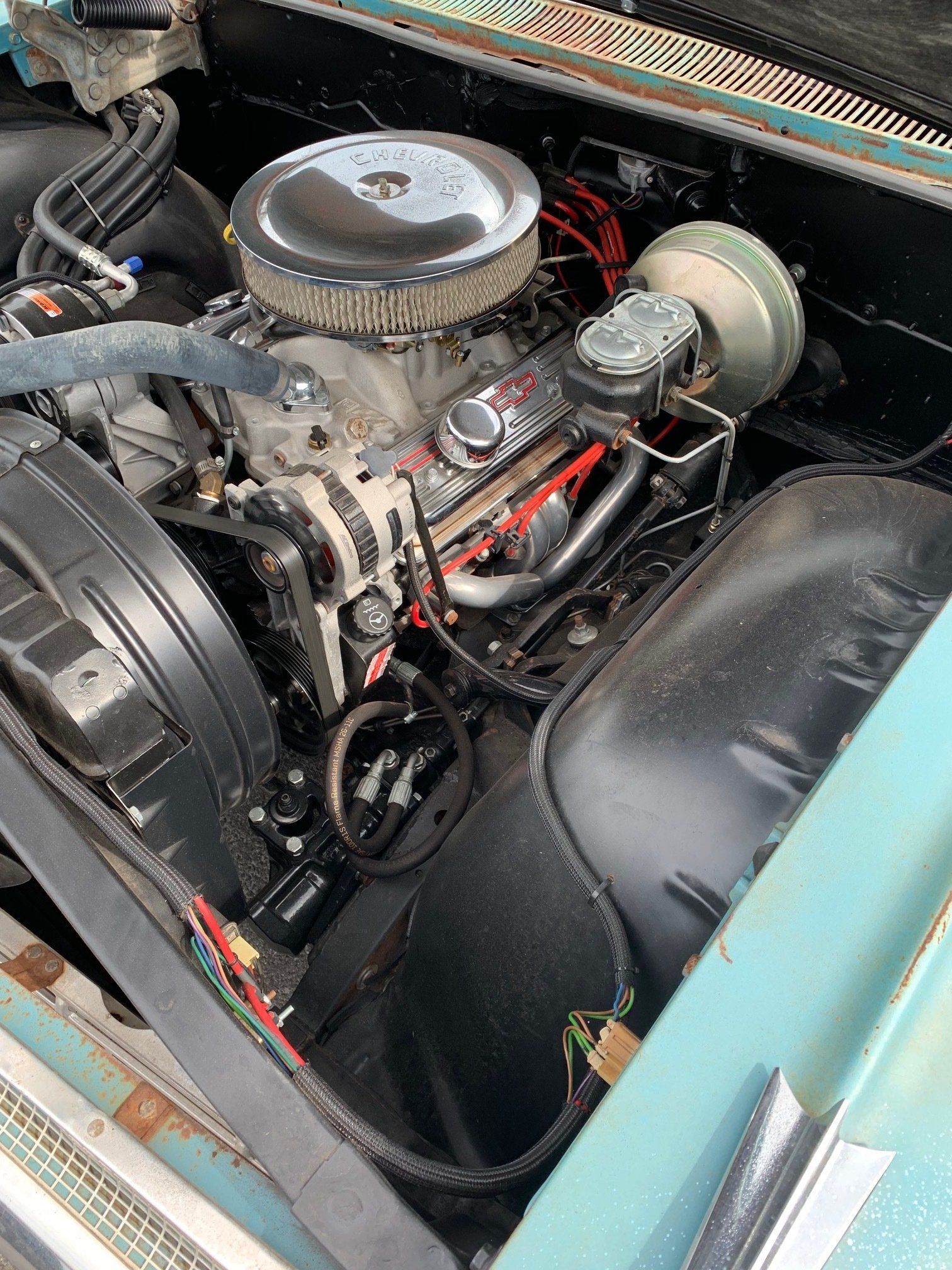 Classic car engine bay with chrome air filter and turquoise body panels