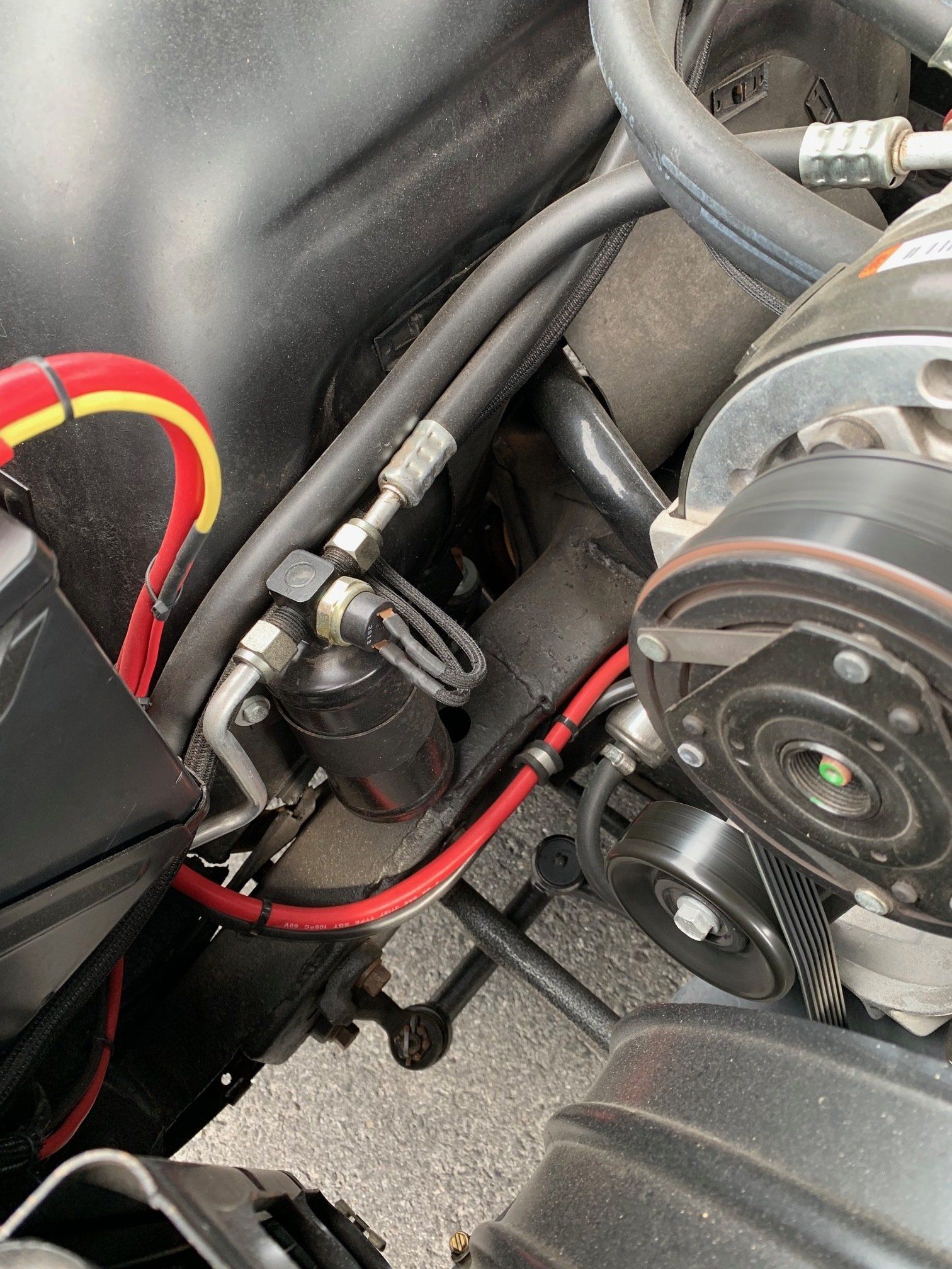 Close-up of car engine components with red wiring and a black pulley assembly