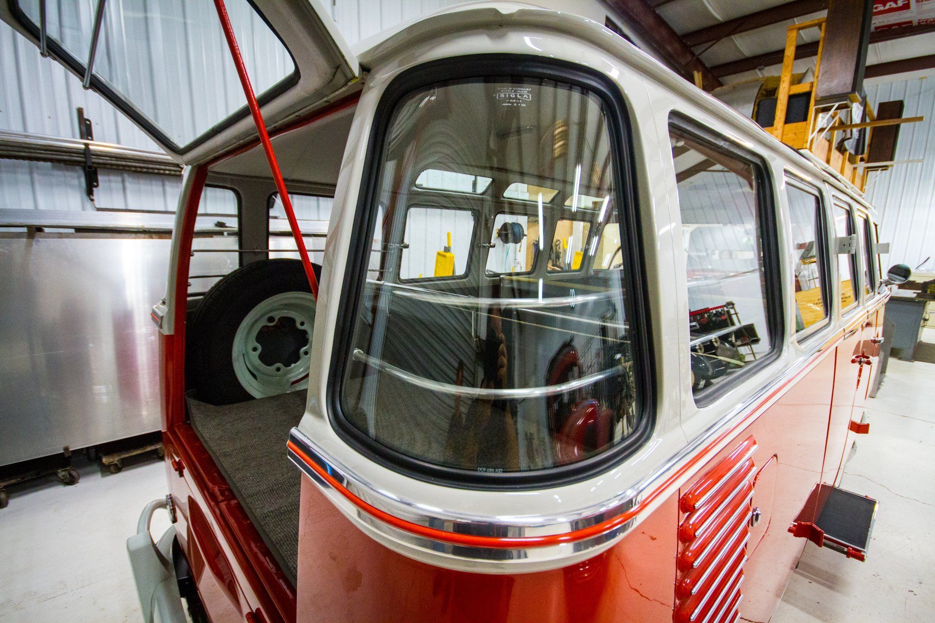 Red-and-white cable car cabin inside a maintenance garage, viewed through the front window.
