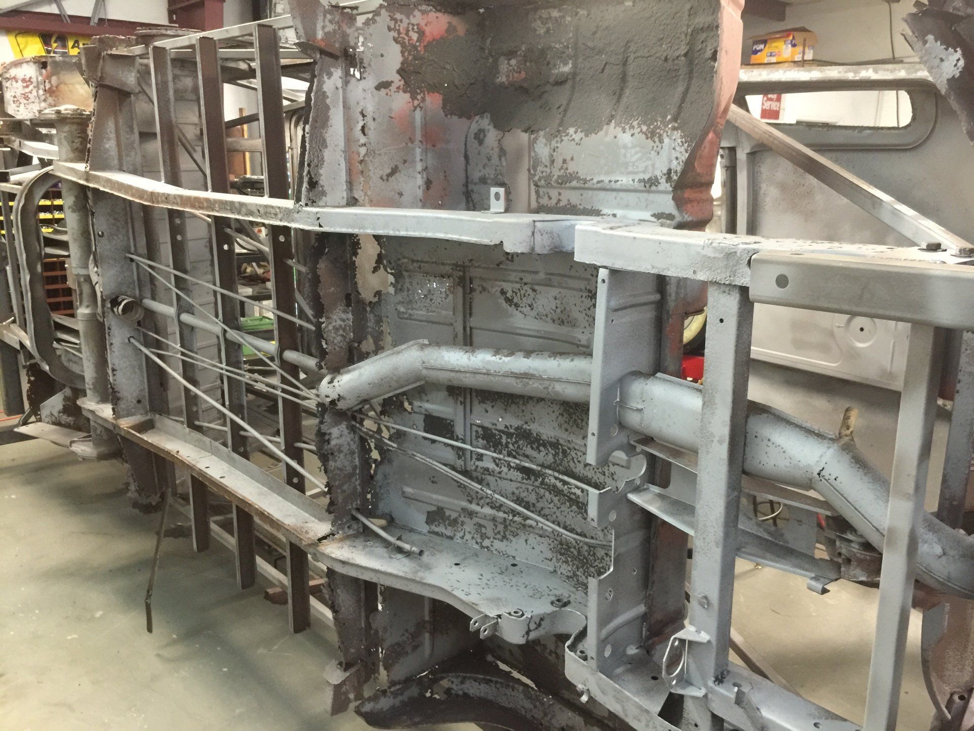 Damaged industrial machinery with exposed pipes, metal framework, and debris in a workshop-like setting