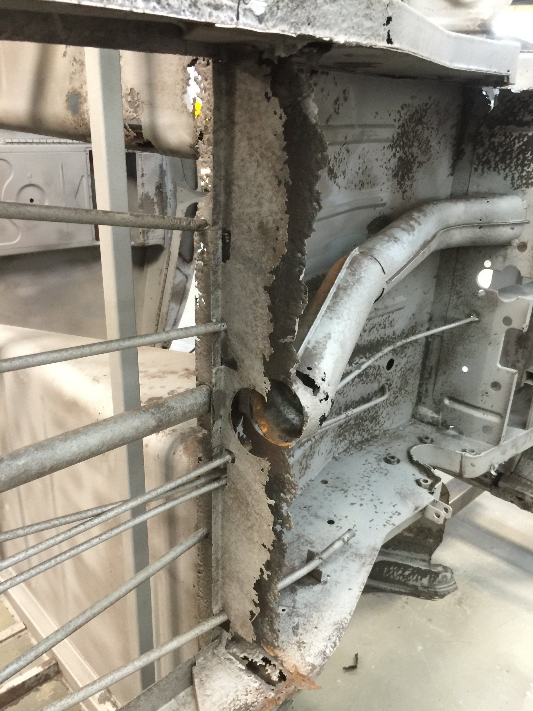 Rusty metal railing with a damaged, corroded support bracket and pipe in an industrial setting