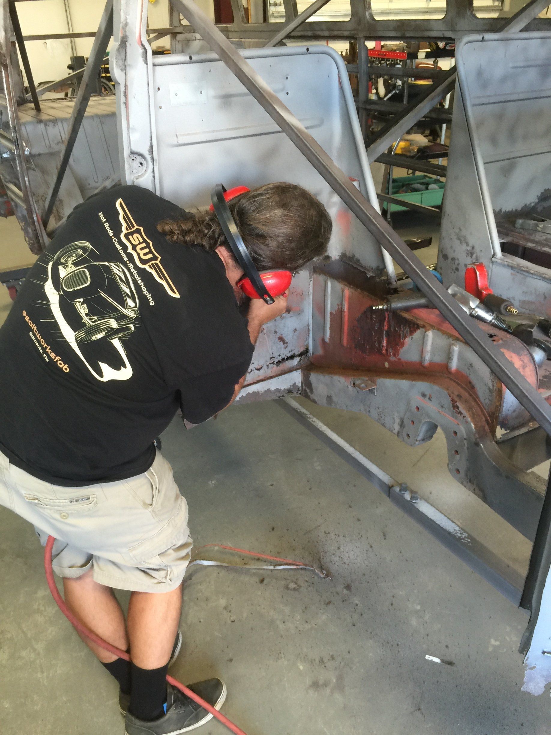 Person in ear protection sanding metal inside a workshop.