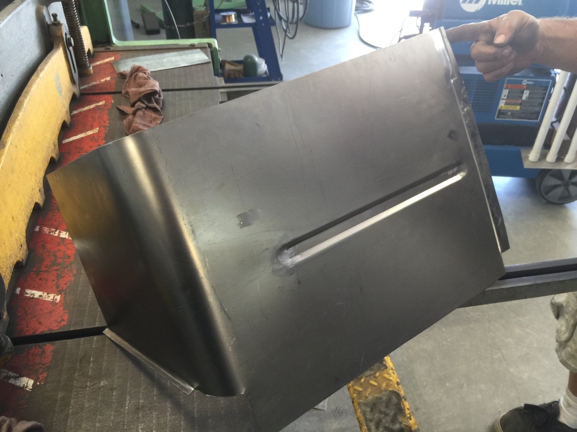 Person handling a large metal sheet in an industrial workshop