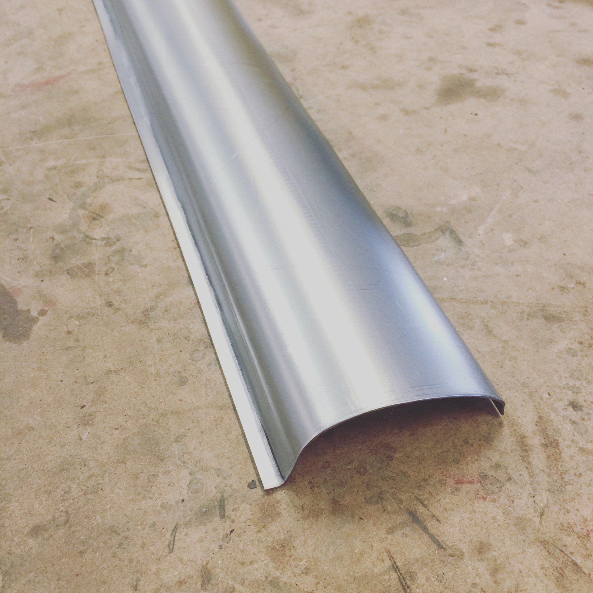 Curved silver metal trim molding on a concrete floor