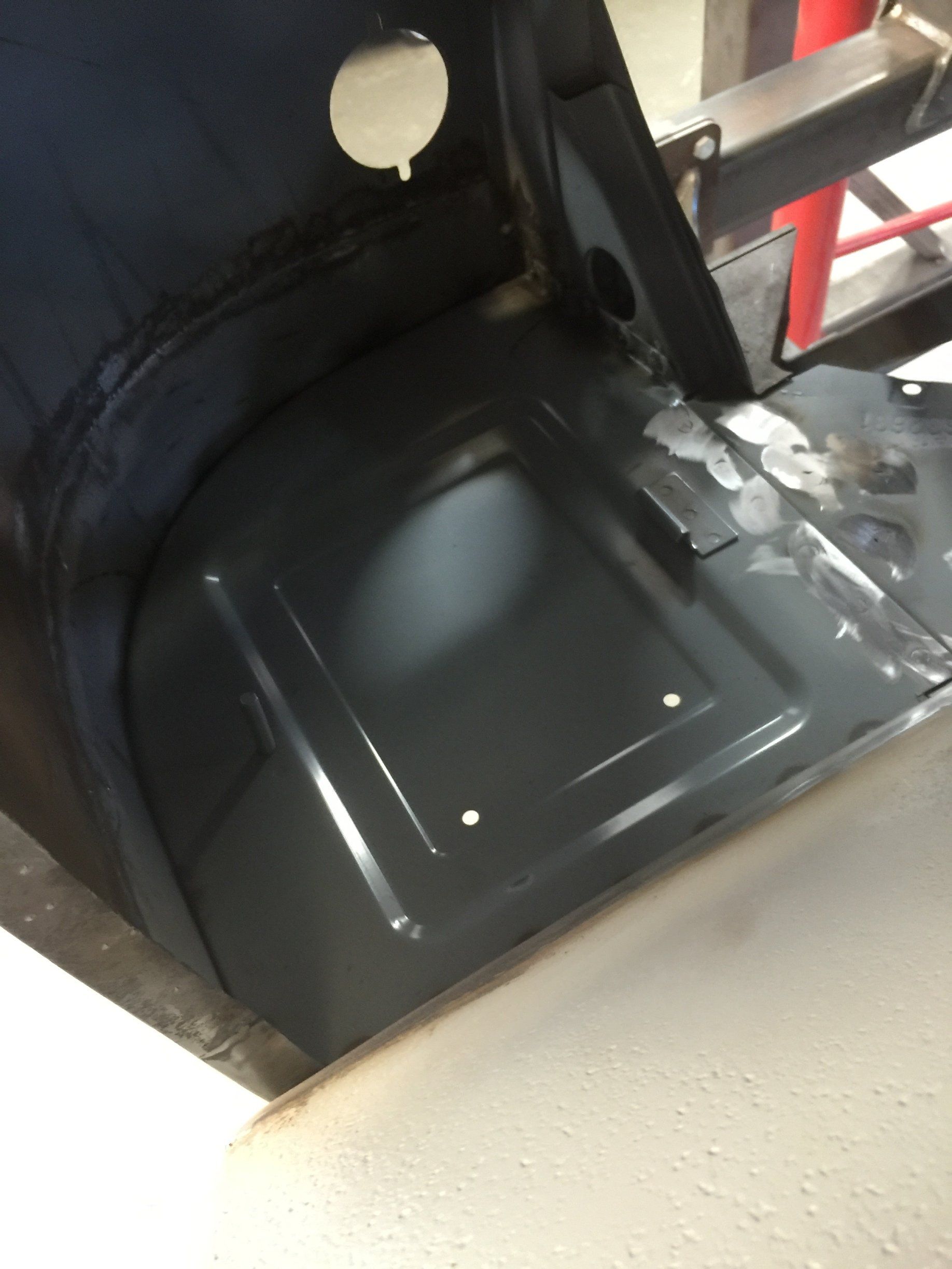 Black molded plastic seat or tray inside a vehicle or machinery cabin, with a round cutout and metal frame.