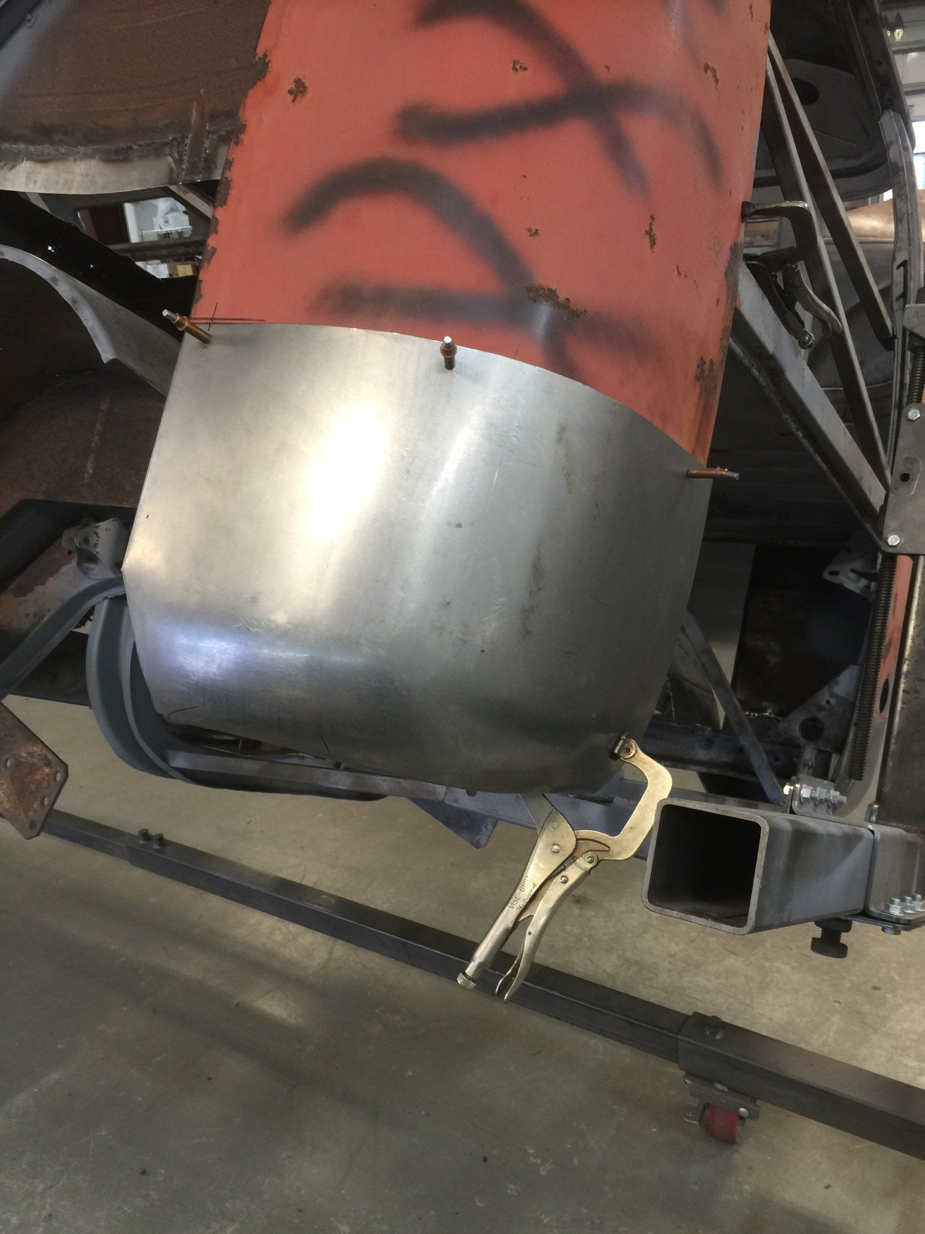 Red metal cylinder with a dented silver lower section mounted on machinery indoors