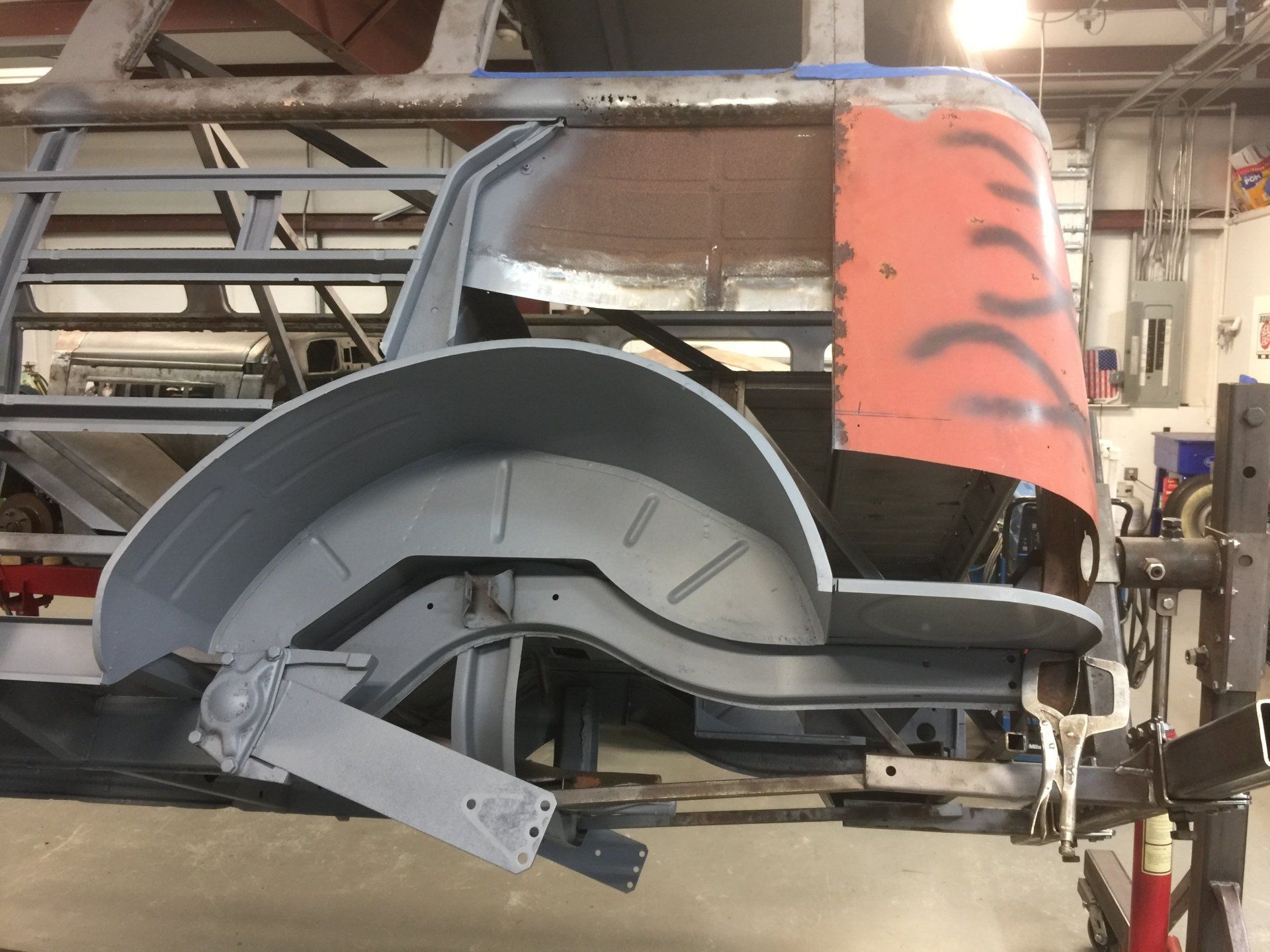 Industrial machine with a large gray circular component and red-orange panel in a workshop.