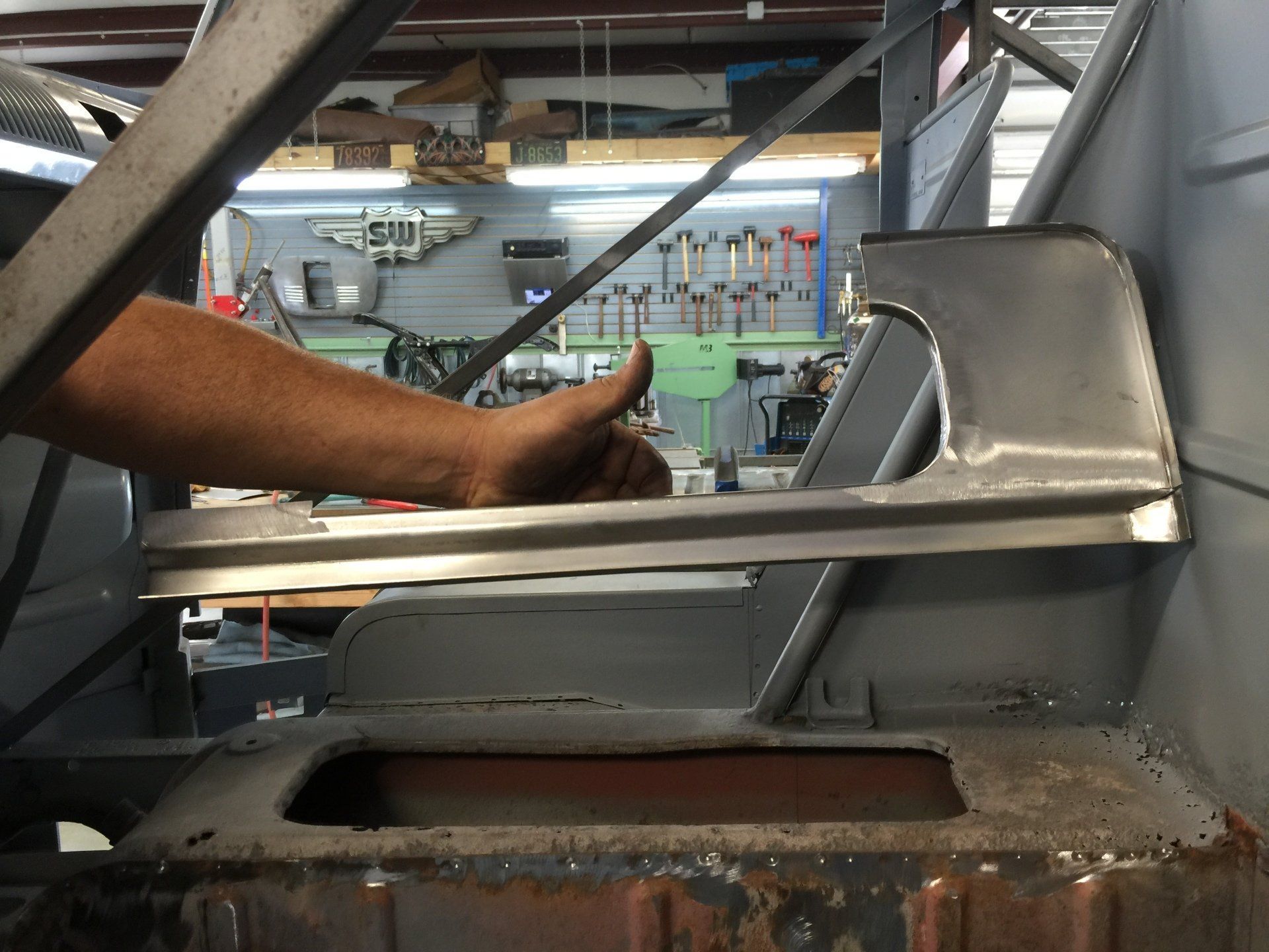 Worker inspecting a metal weld in a factory, with machinery and beams in the background