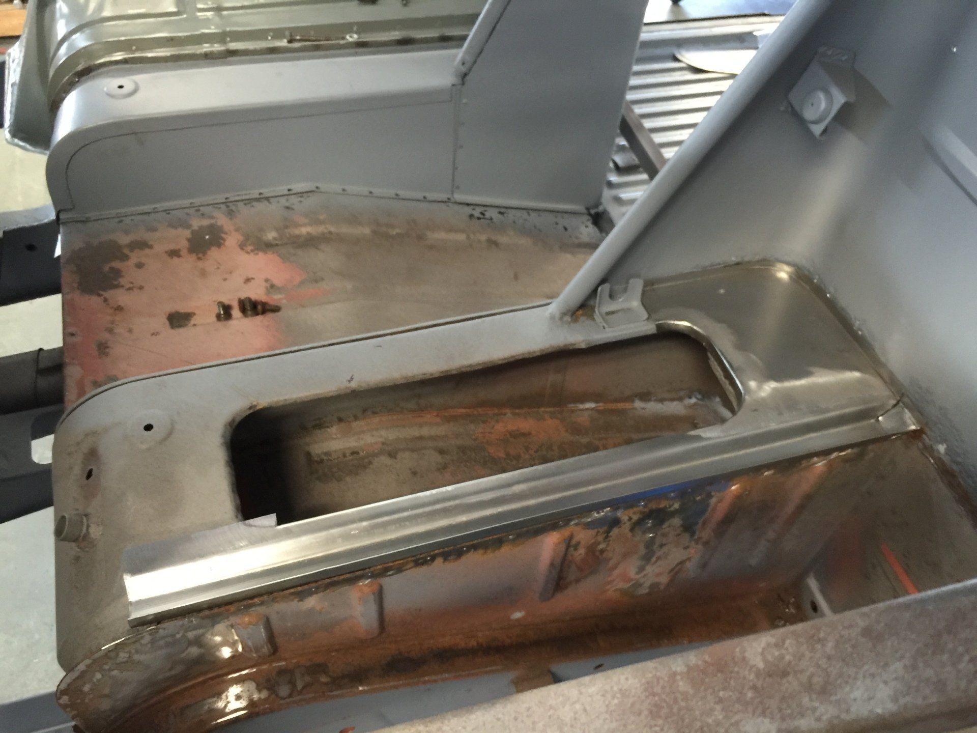 Close-up of a rusted metal industrial part with a slot and welded seam inside a machine or assembly line