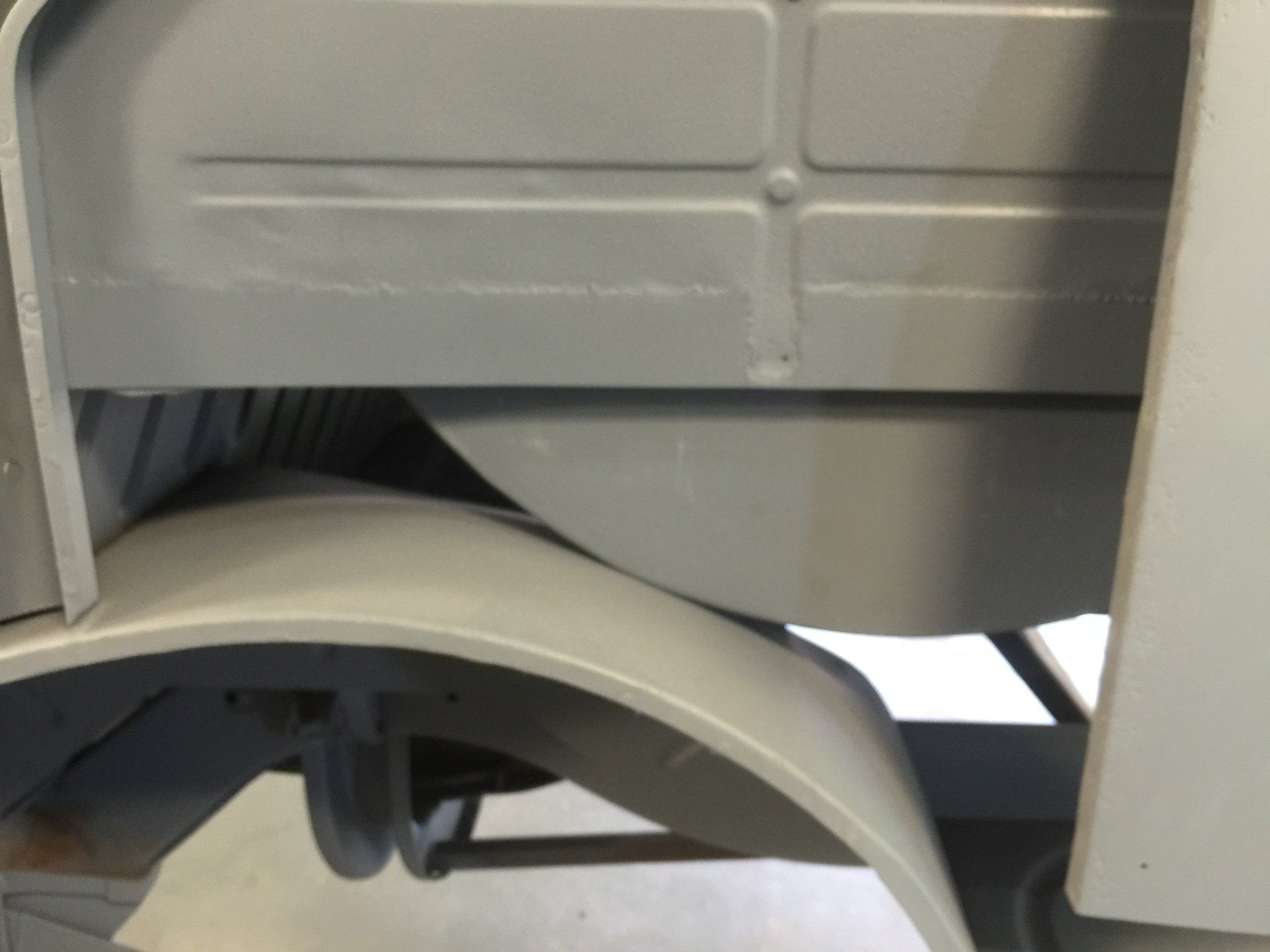 Close-up of a white appliance’s lower panel and curved base cover.