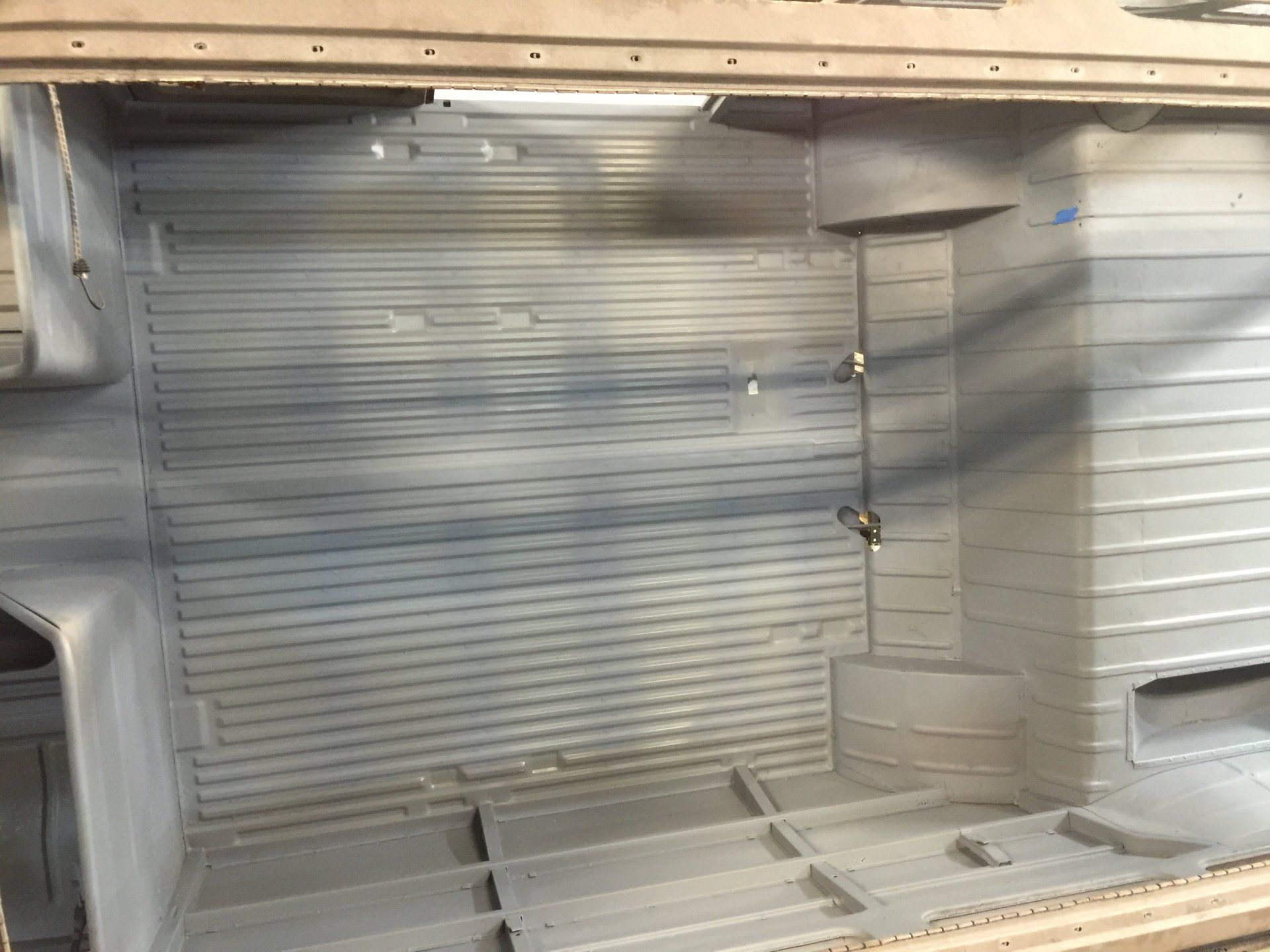 Empty metal cargo van interior with corrugated walls and open rear floor space