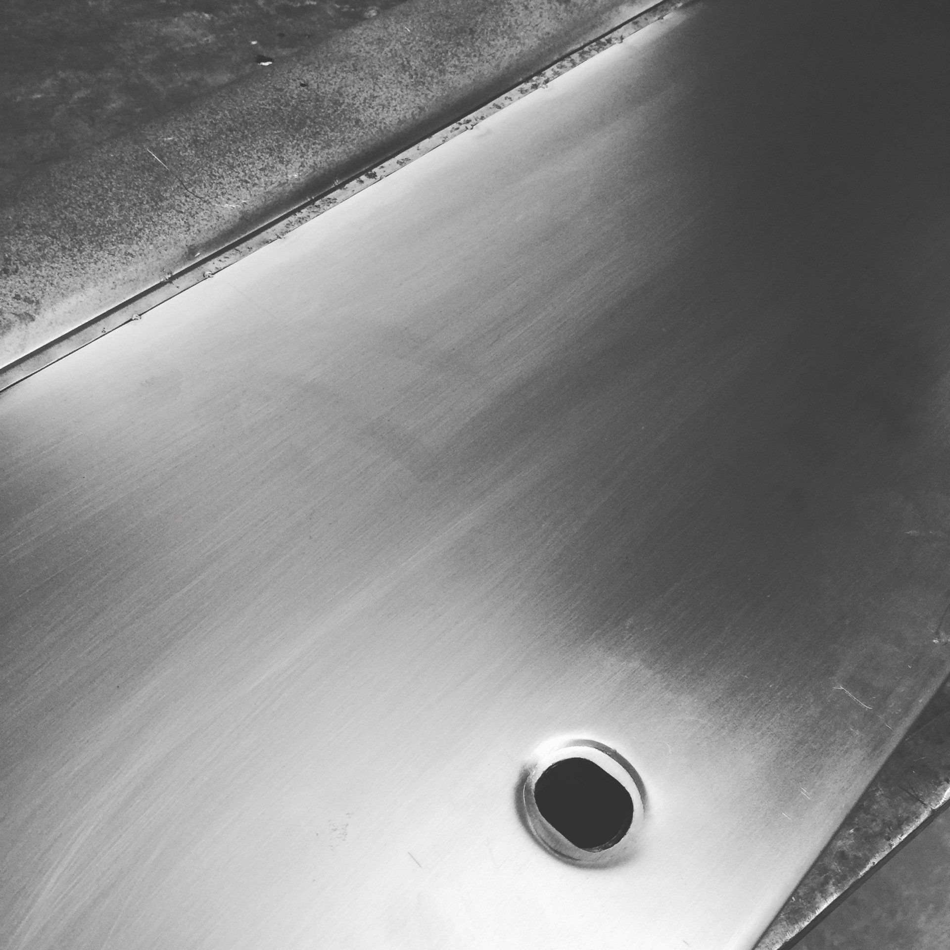 Stainless steel sink with a round drain hole, shown in close-up.