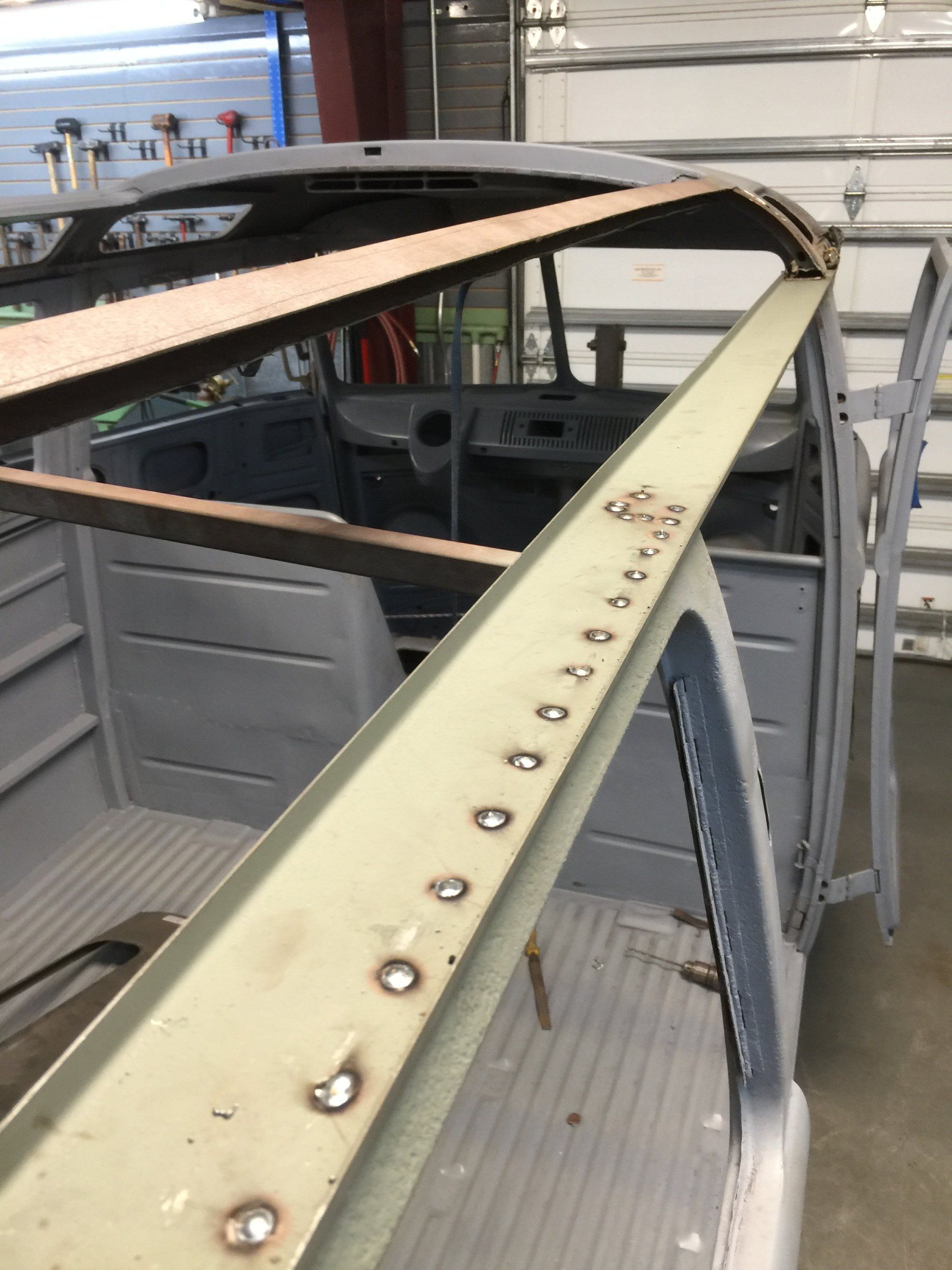 Damaged car frame with long wooden beams attached, outdoors in a repair yard