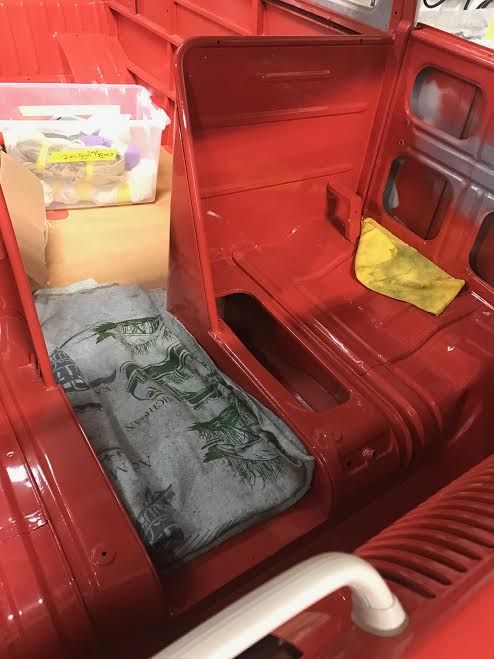 Red vehicle interior with red walls, a gray mattress, yellow cushion, and storage boxes.