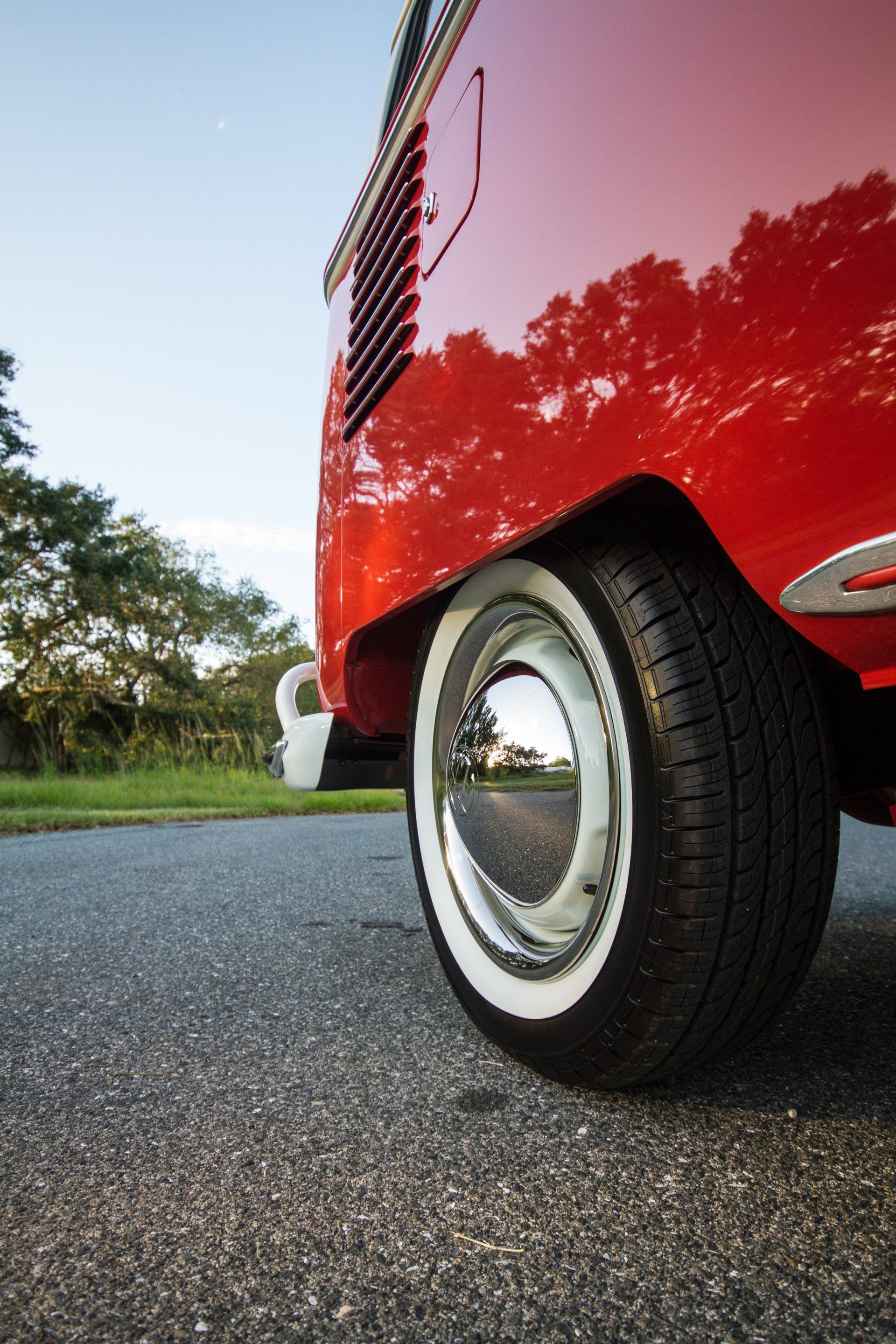 Close-up of a red vintage car’s rear wheel parked on asphalt outdoors