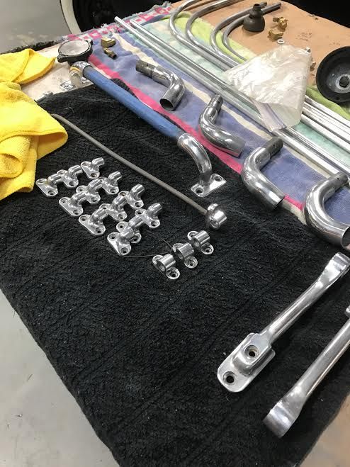 Assorted chrome hand tools and fittings laid out on a black towel on a workbench.