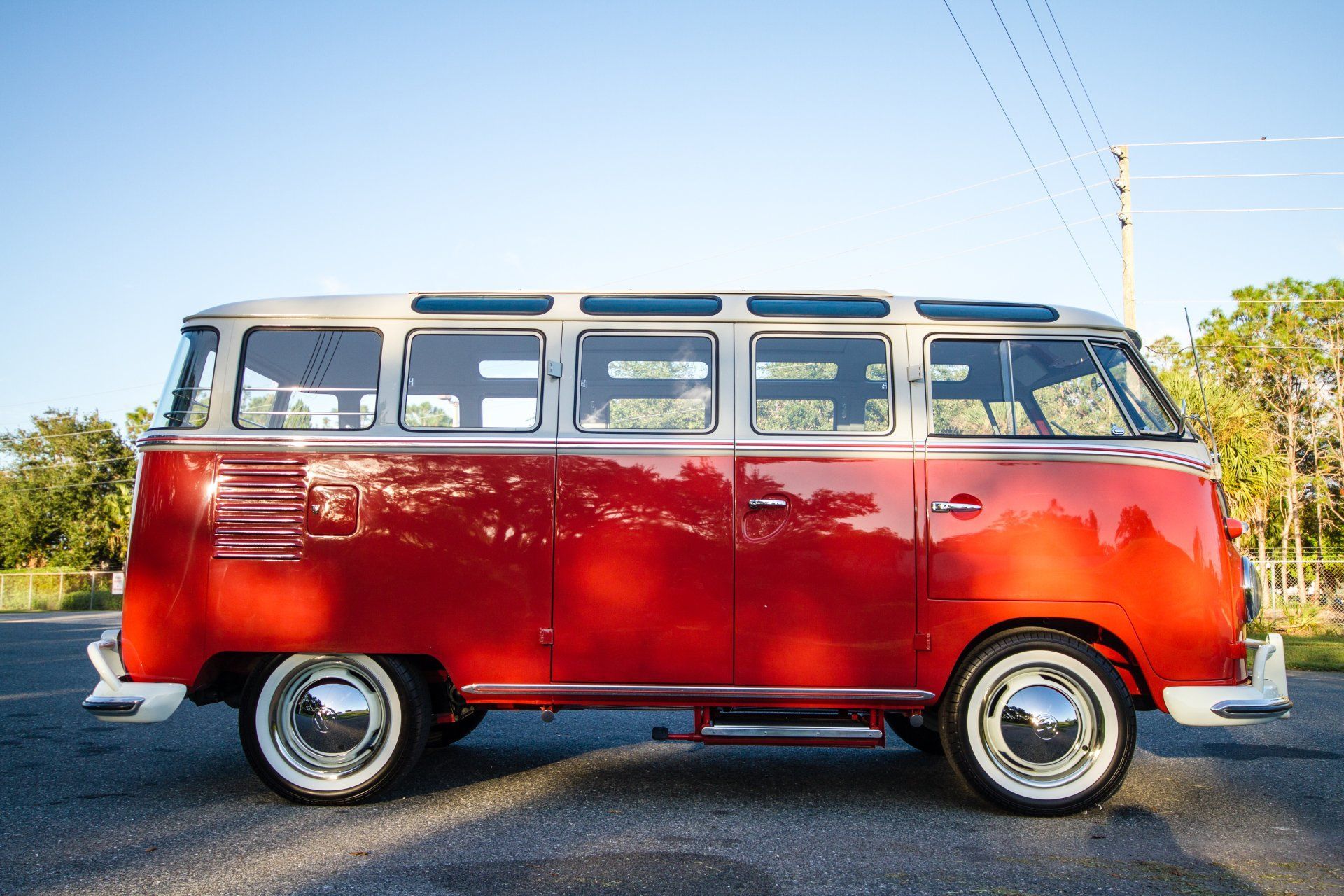 Red vintage bus parked on a road under a blue sky.