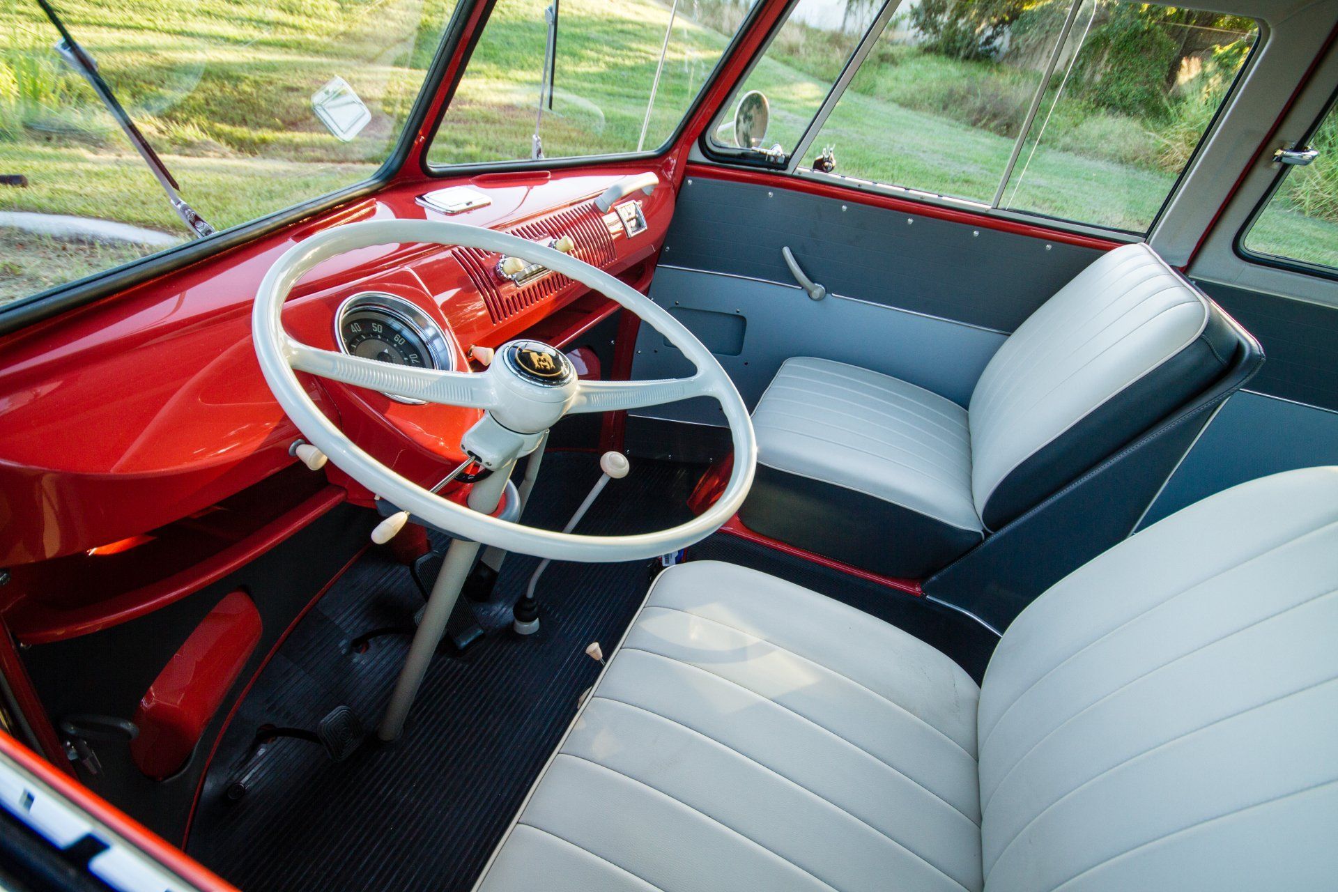 Vintage red car interior with white steering wheel and light blue seats, viewed from the front seat