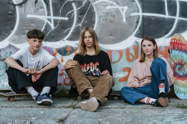 Group of five smiling teens with arms around each other, outdoors.