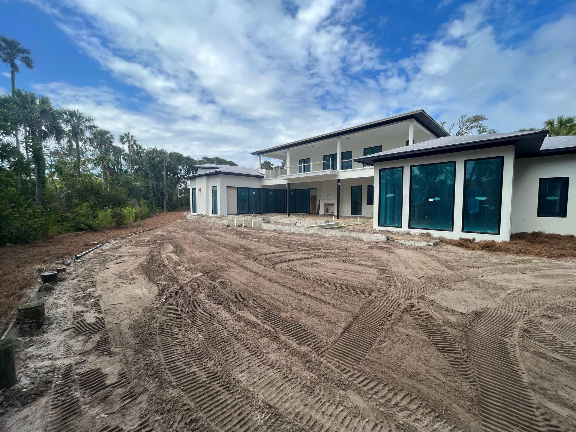 A large house is being built in the middle of a dirt field.