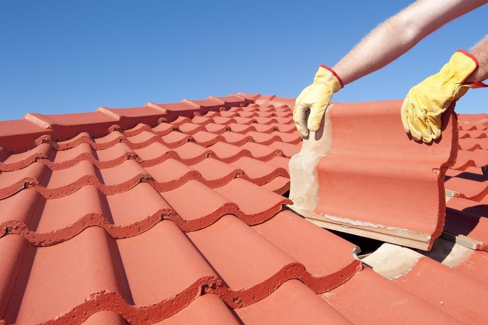 A Person Wearing Yellow Gloves Is Working on A Roof — Bradley Roofing in Tuncurry, NSW