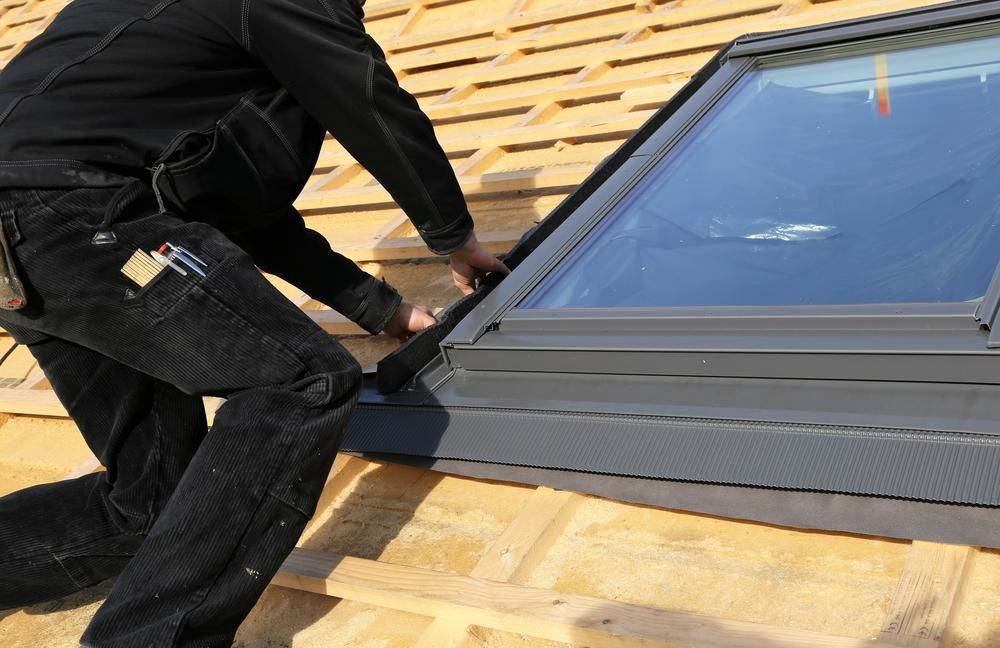 A Man Is Installing a Skylight on A Roof — Bradley Roofing in Tuncurry, NSW